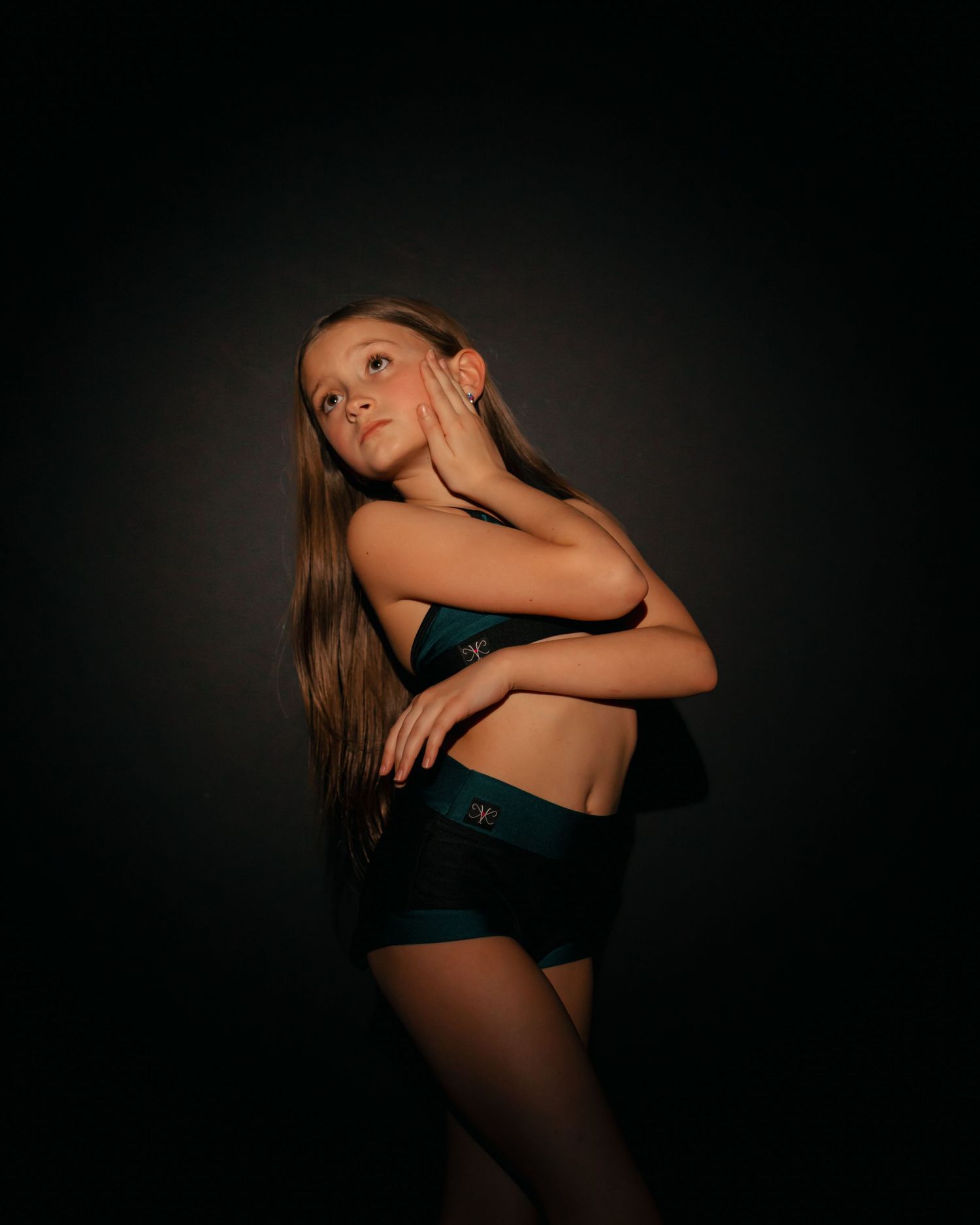 A figure in black lingerie poses dramatically against a dark background in a series of artistic boudoir shots.