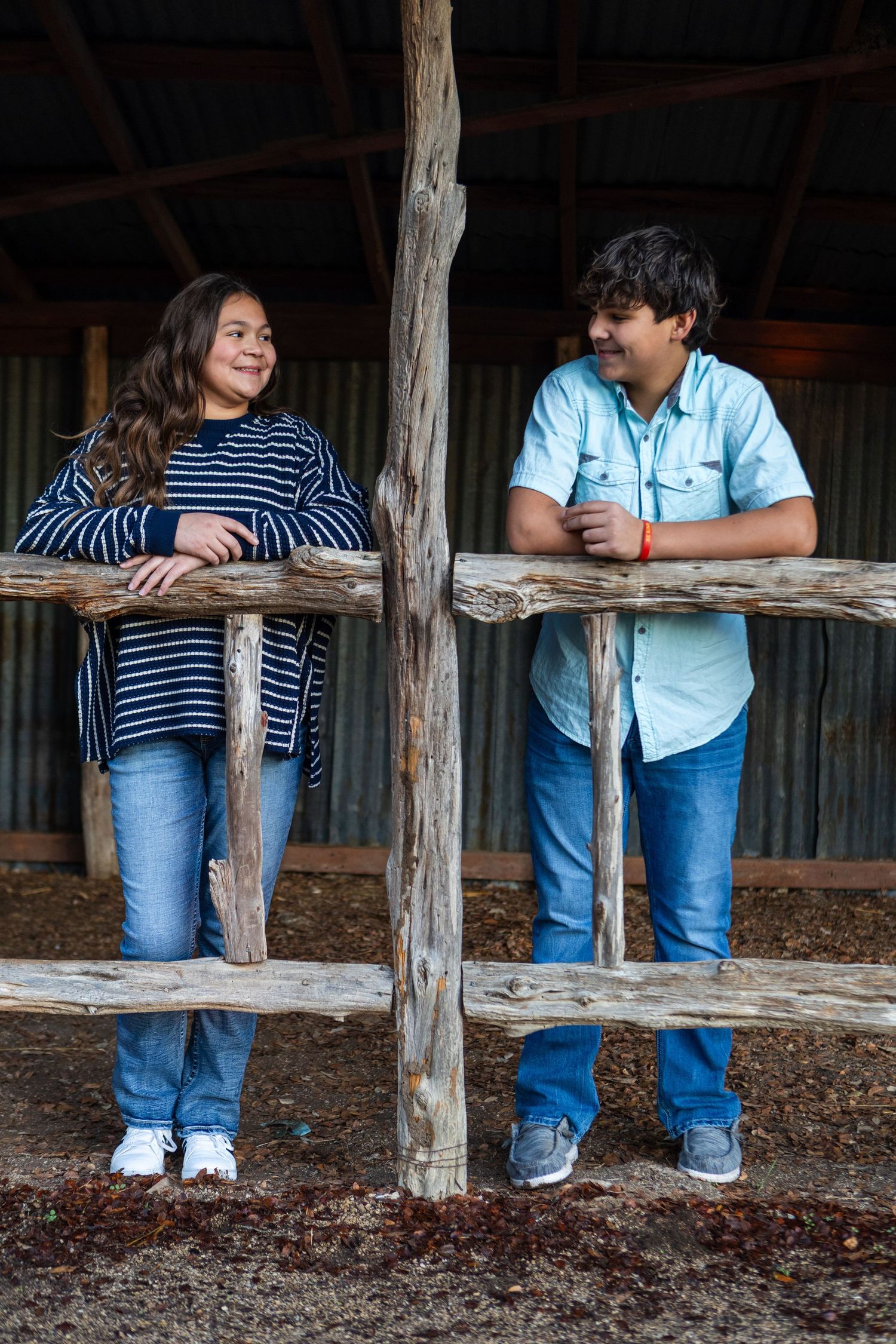 Romantic couple in casual wear leaning on rustic wooden fence posts in a sequence of intimate poses.