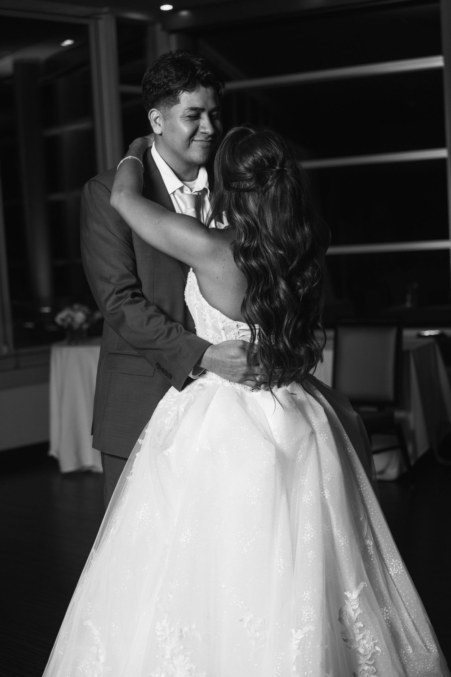 Black and white photo of a bride and groom sharing their first dance at a wedding reception.