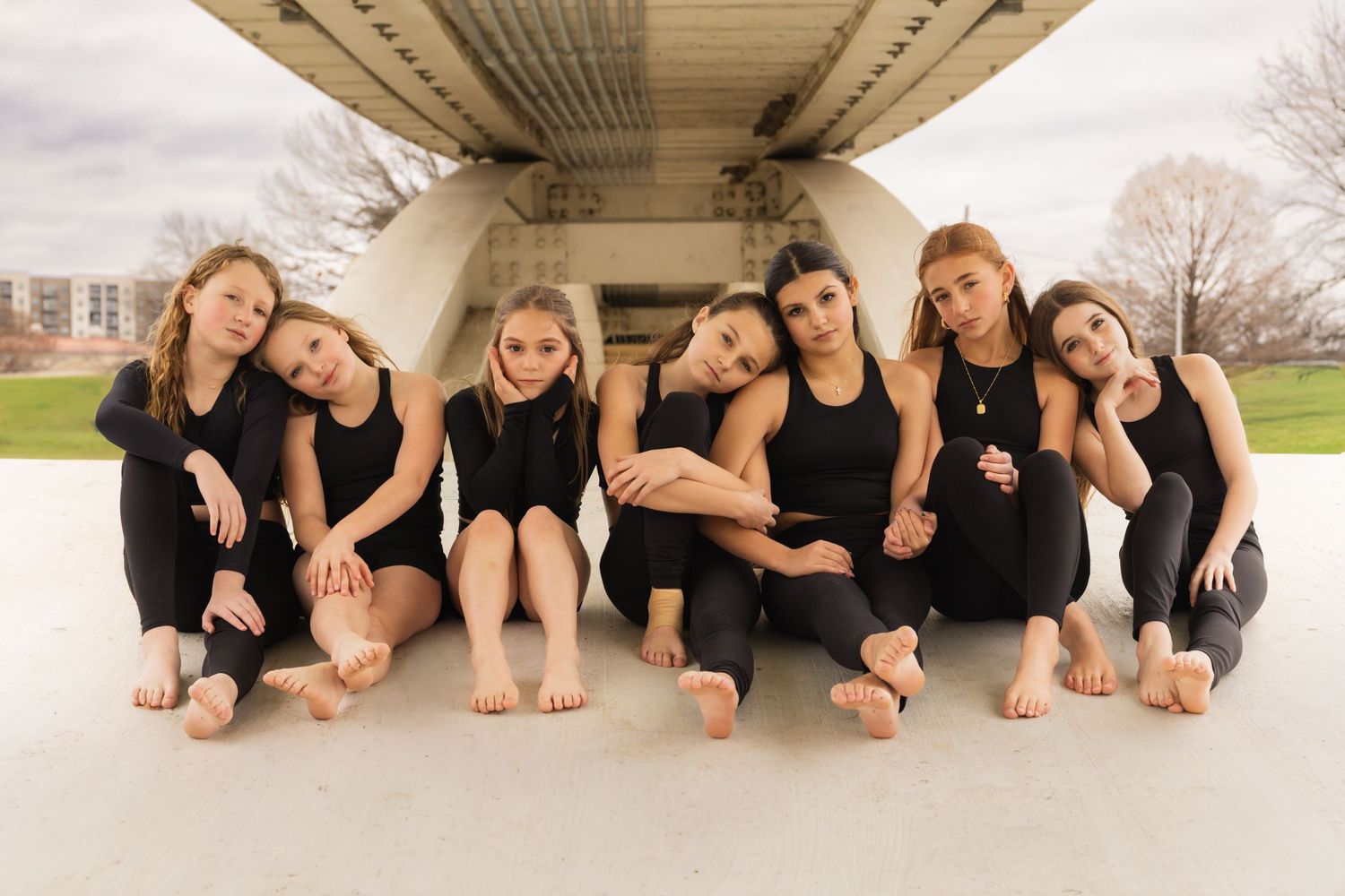 Group wearing black outfits lying together on floor in artistic dance formation.
