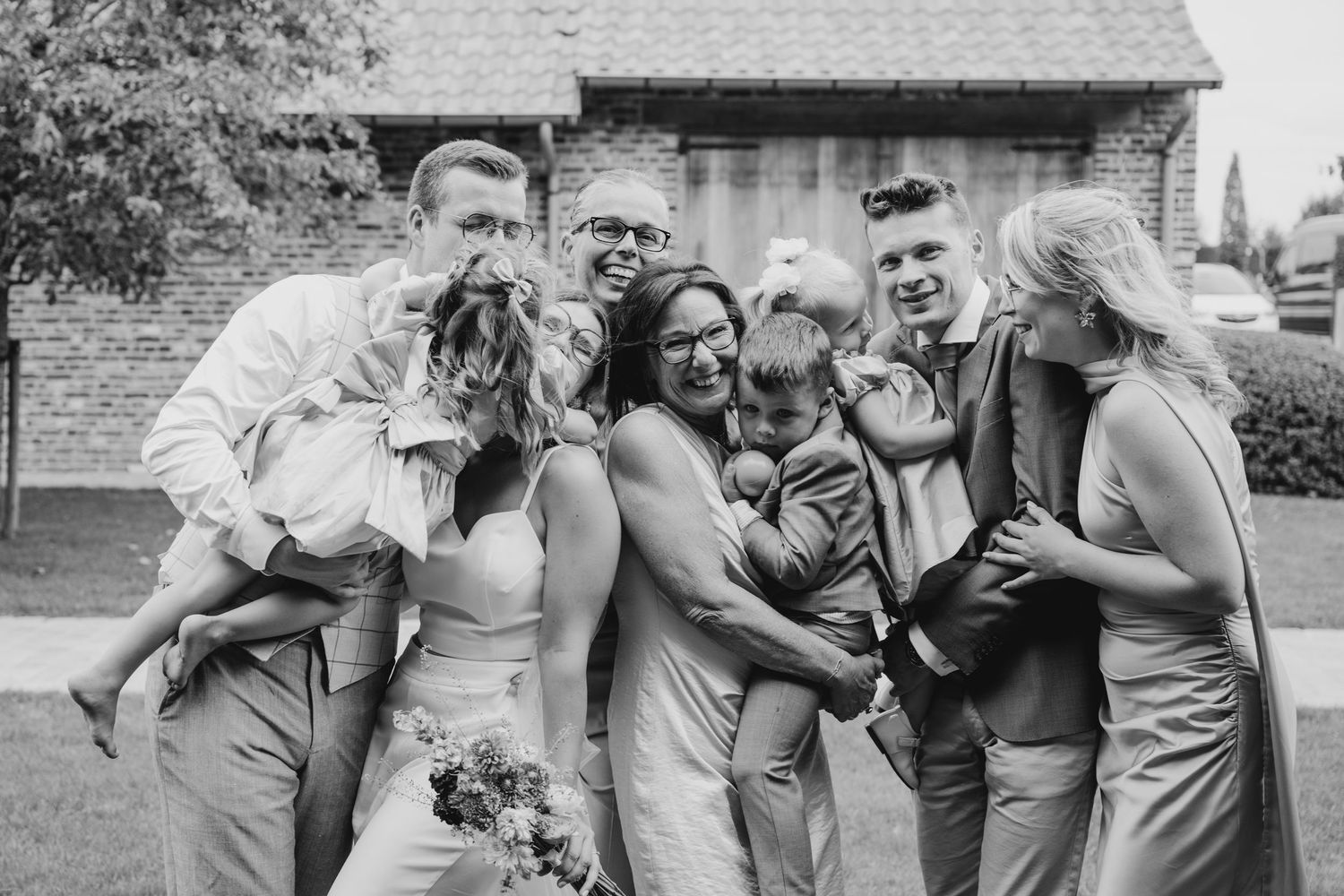 Wedding party in coordinated gray outfits posing together outdoors.