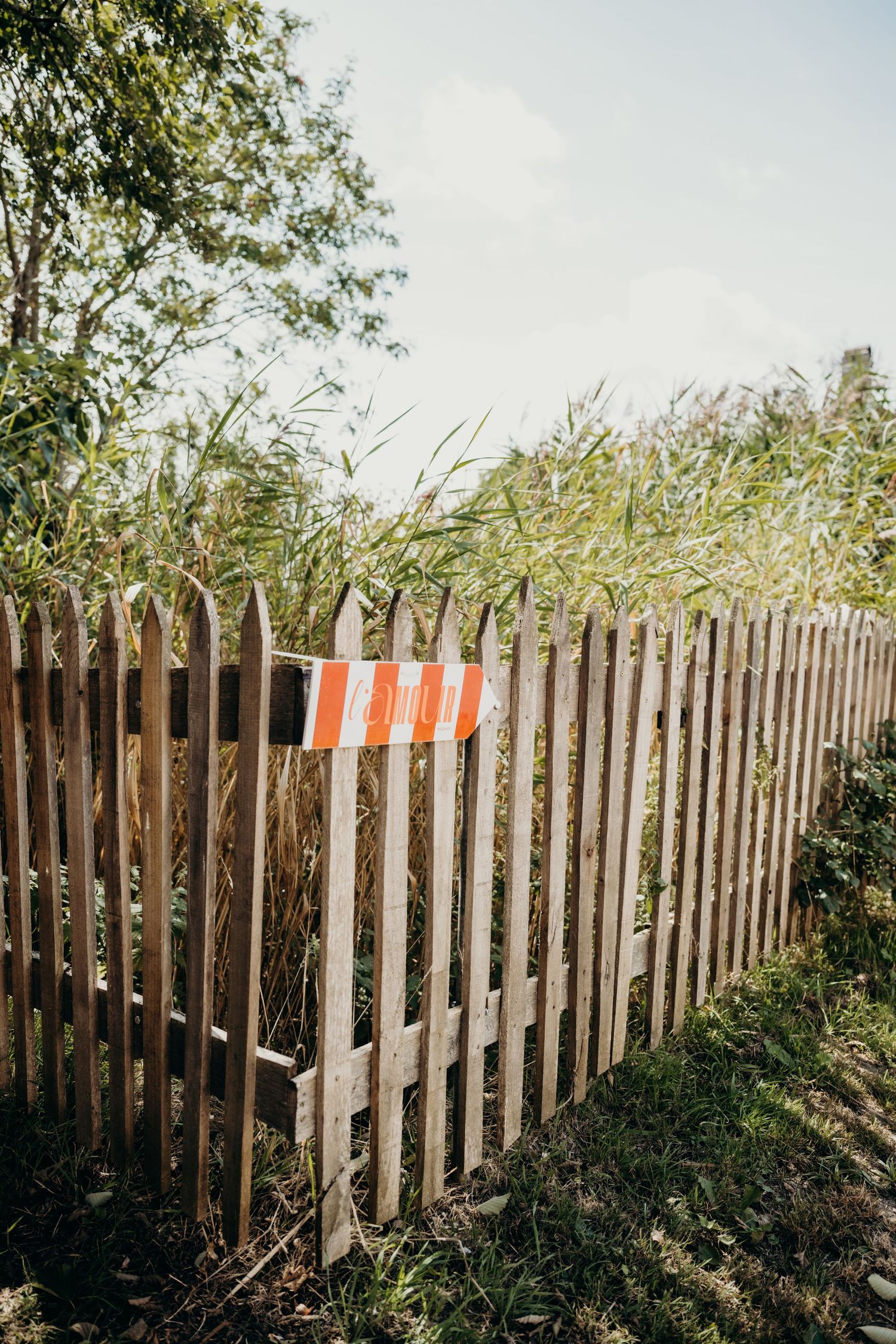 Wooden picket fence against blue sky with rustic countryside charm.