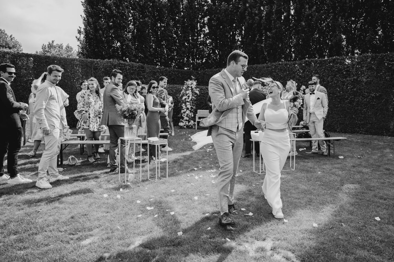 Wedding guests gather on a grassy lawn for an outdoor celebration.