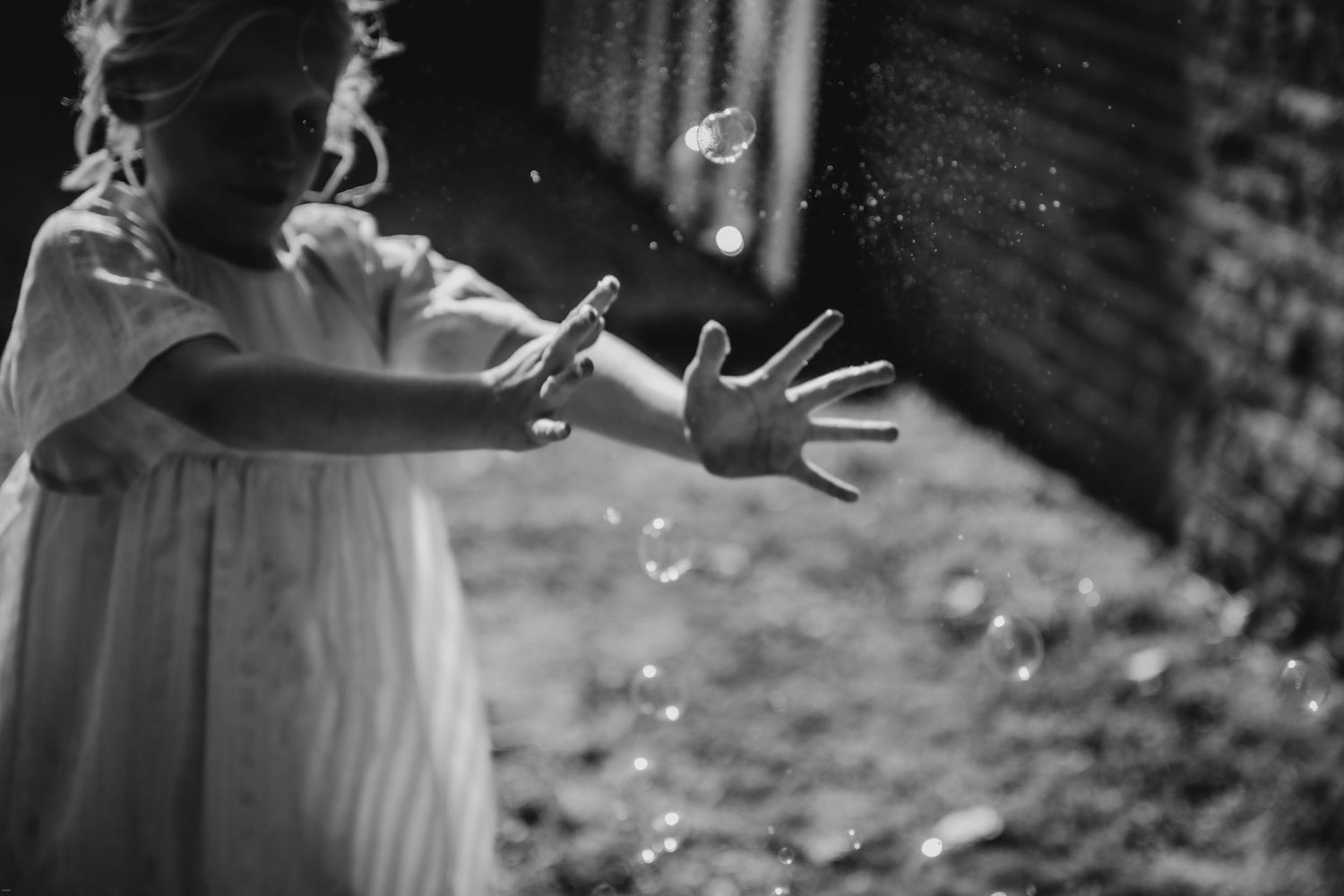 Black and white image of soap bubbles floating in the air at an outdoor celebration.