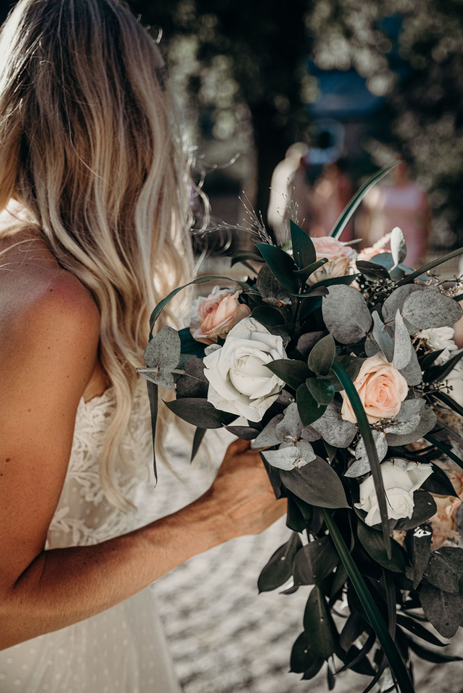 Wedding bouquet featuring white roses and dark green eucalyptus leaves.