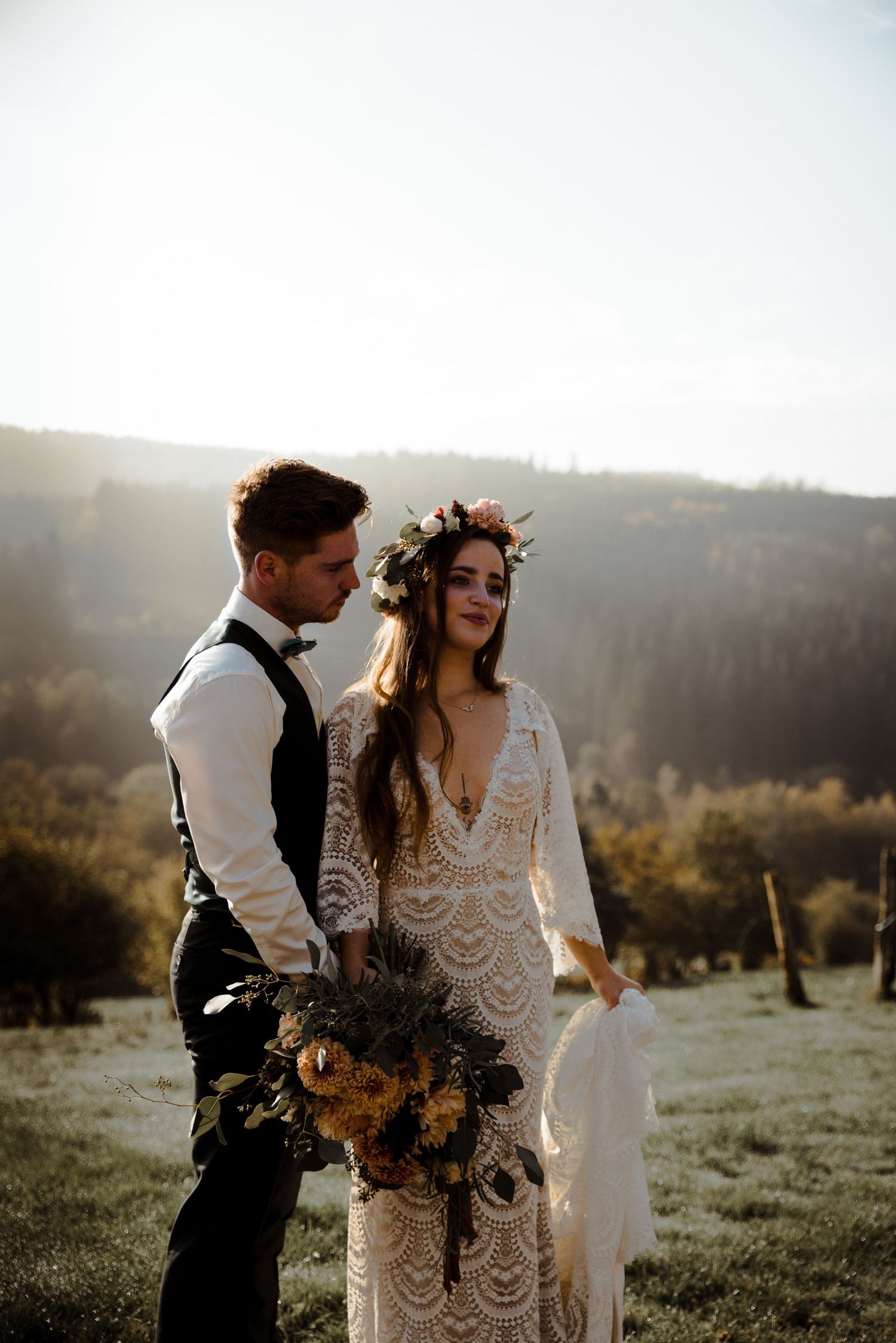 Rustic outdoor wedding portrait in golden sunlight with mountain views.