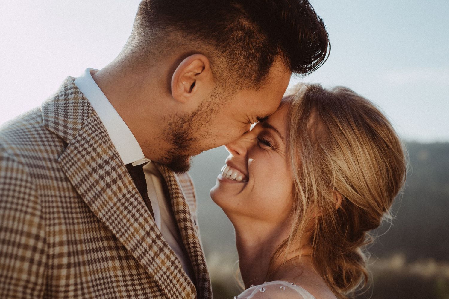 Romantic close-up of couple sharing tender moment against mountain backdrop.