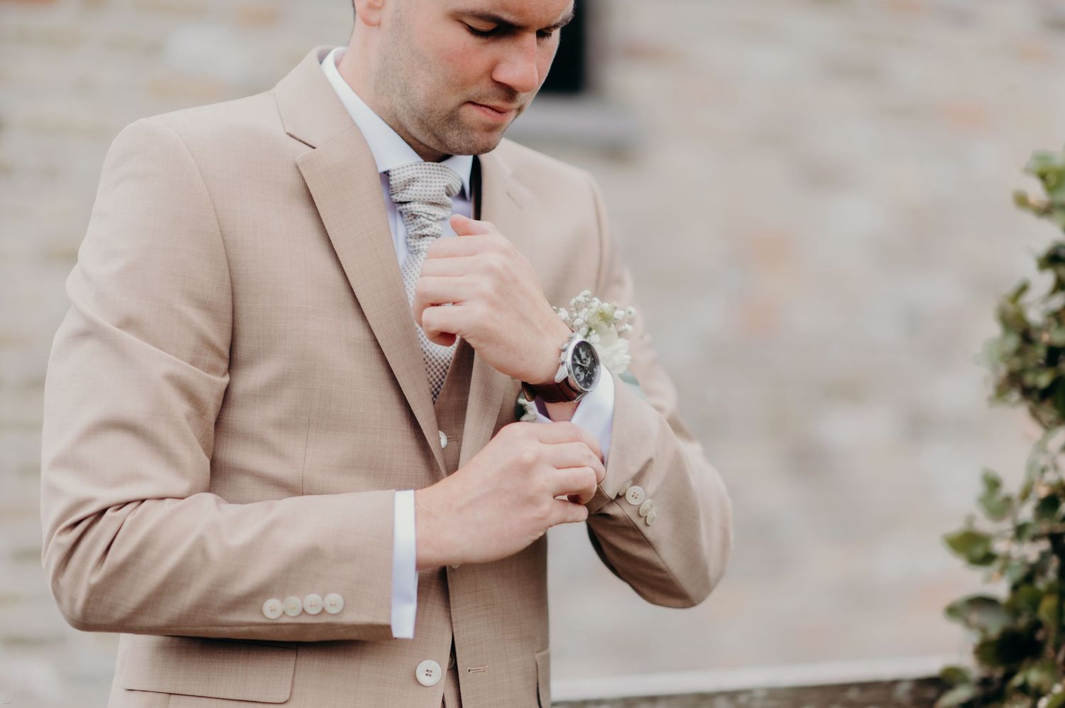 Detail shots of a beige suit jacket with boutonniere being adjusted.