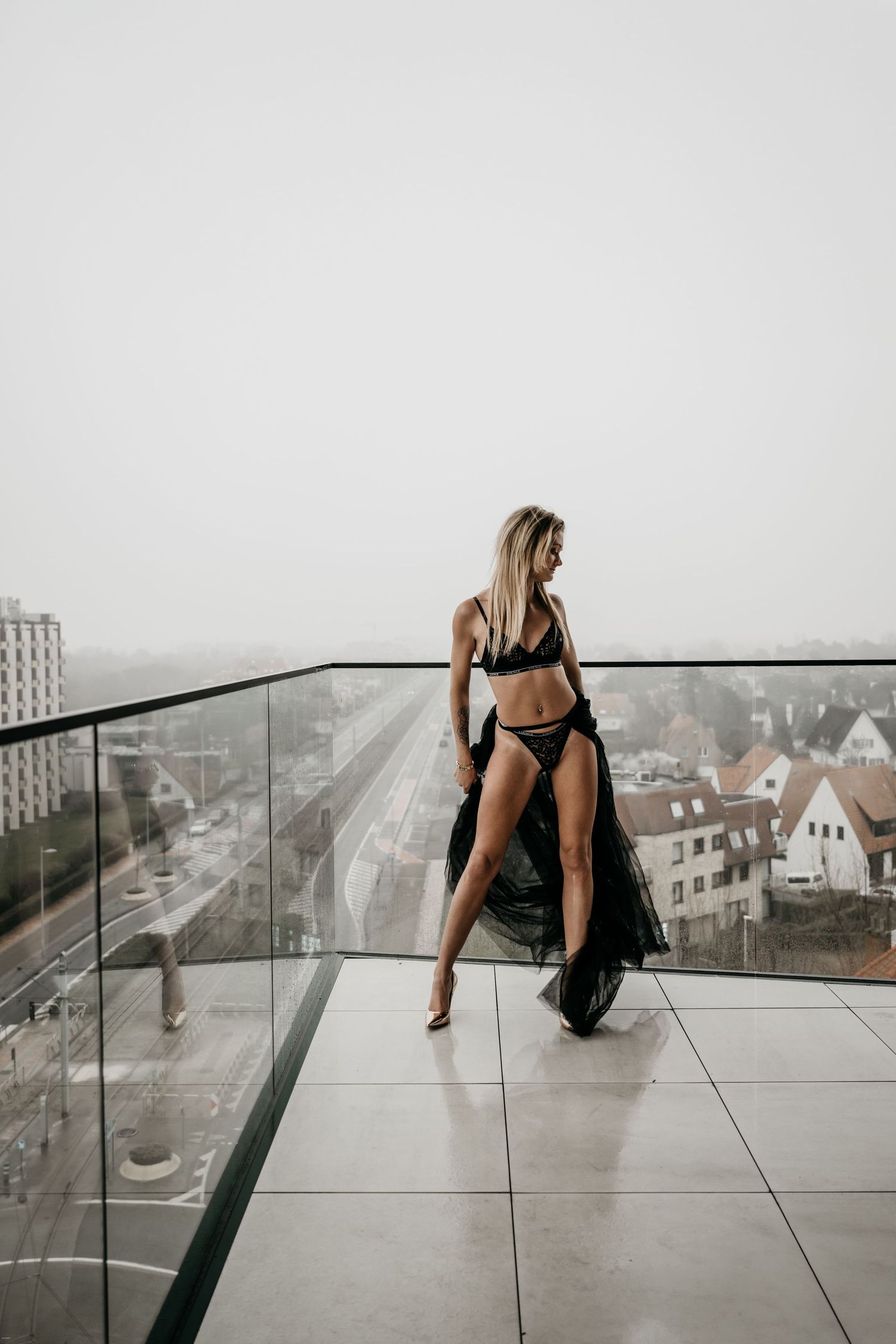 A sequence of moody black and white photos showing someone sitting on the edge of a balcony overlooking a cityscape.