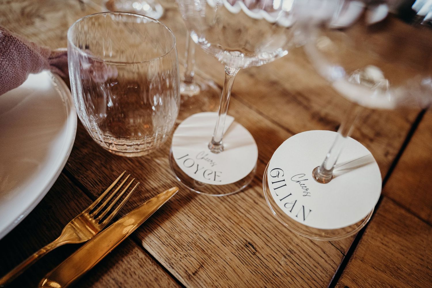 Wine glasses with personalized name tags arranged on a wooden surface.