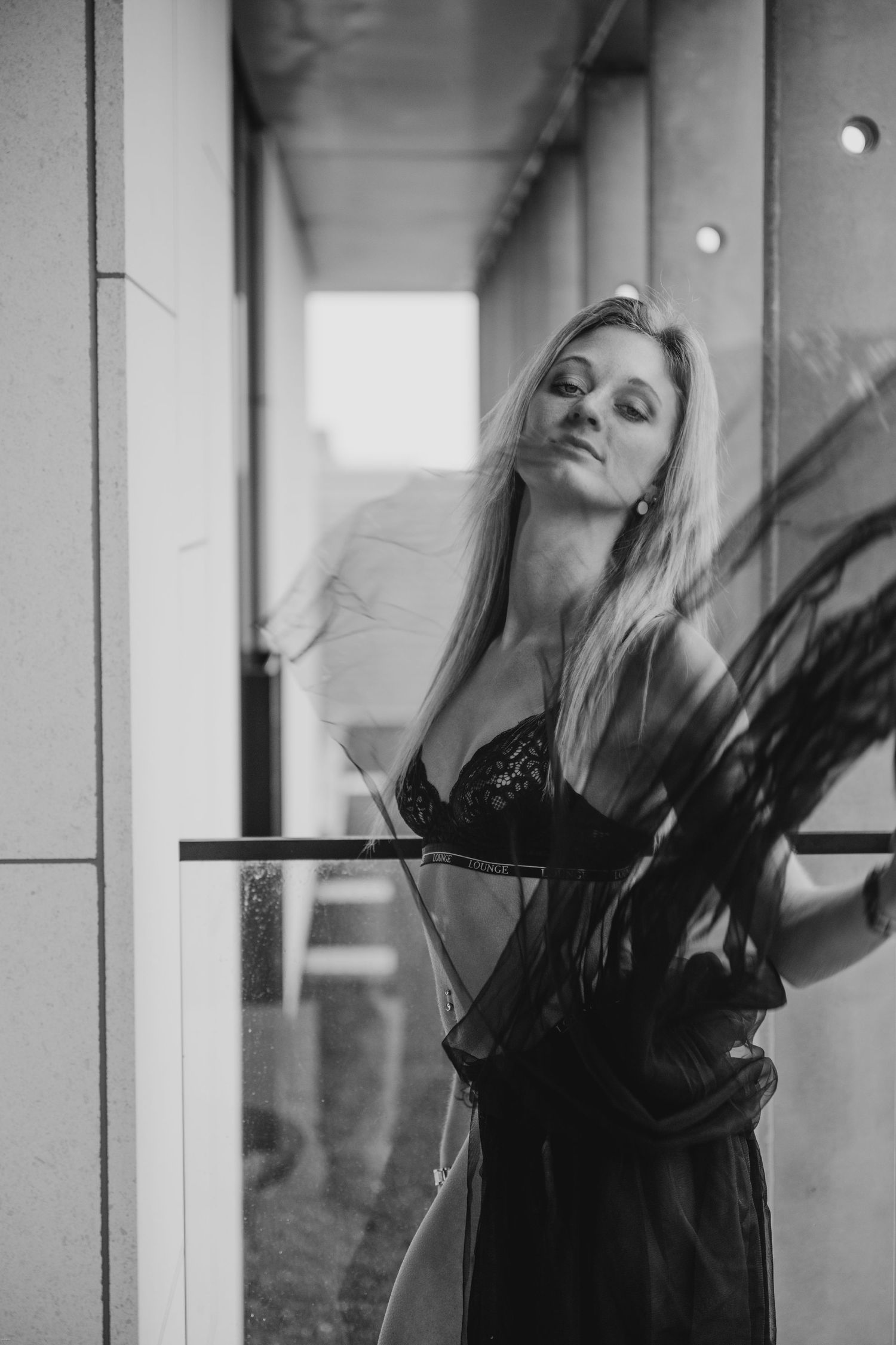 Artistic black and white portrait series showing graceful movement against a window with dramatic lighting.