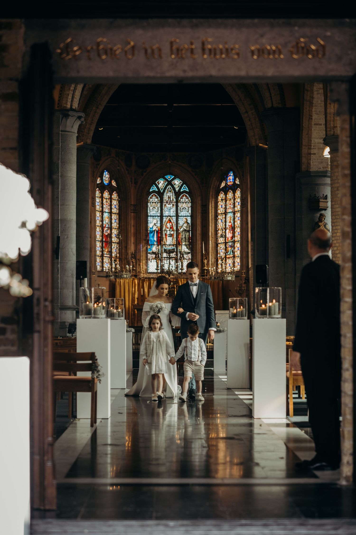 Gothic church interior with stained glass windows and white decorations for a wedding ceremony.