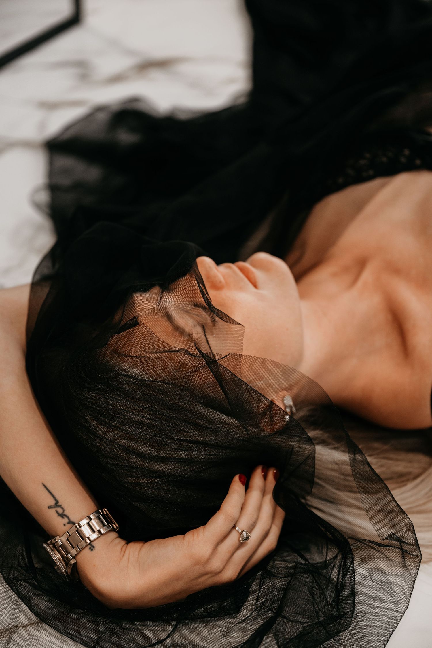 Artistic portrait series showing a person with dark hair lying down against a light background in dramatic lighting.