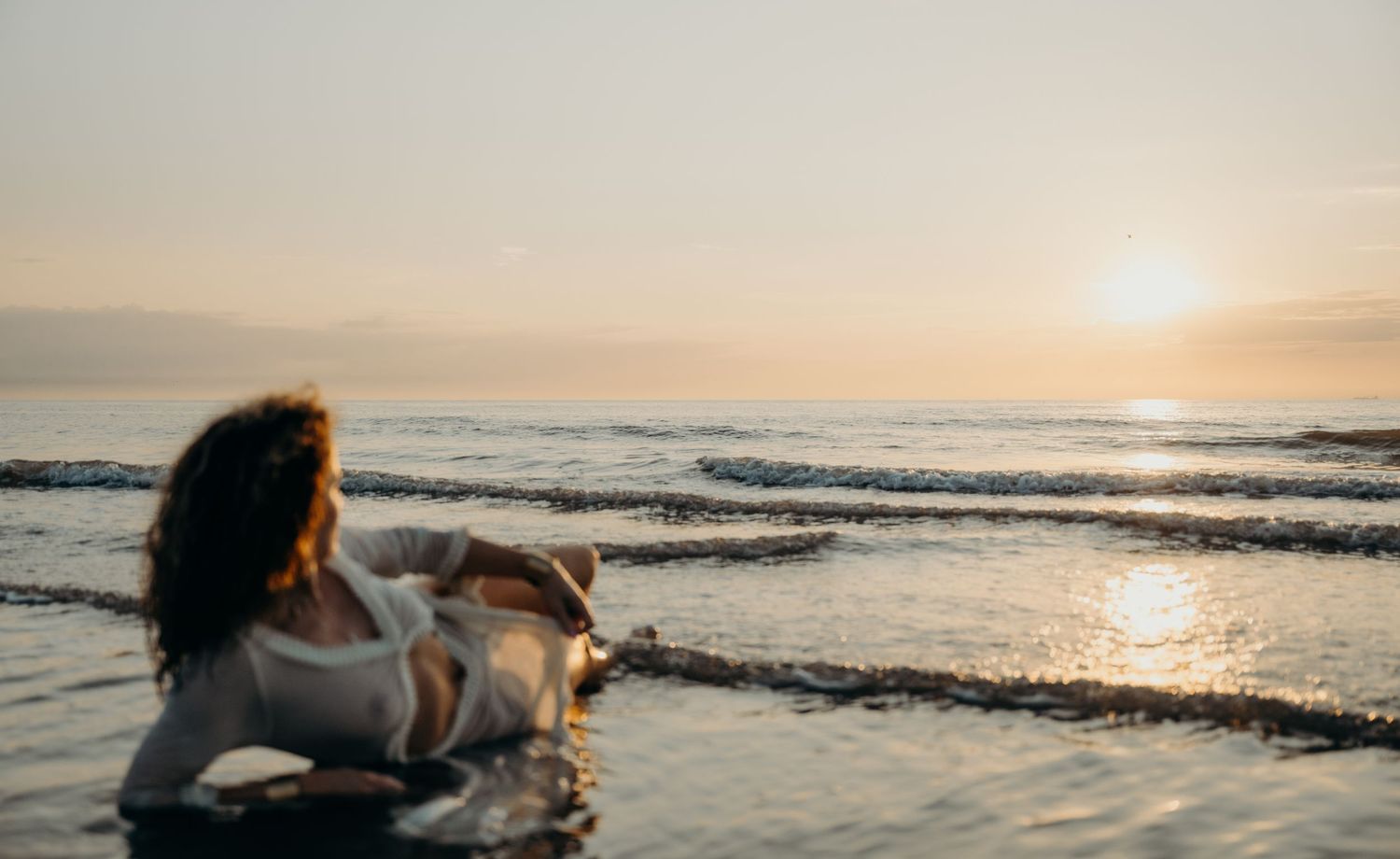 Scenic beach landscape at sunset with waves crashing on the shore.