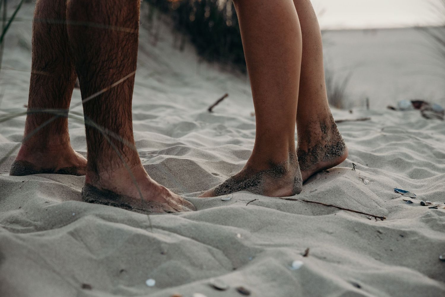 Series of minimalist photographs showing feet standing in sand at the beach.