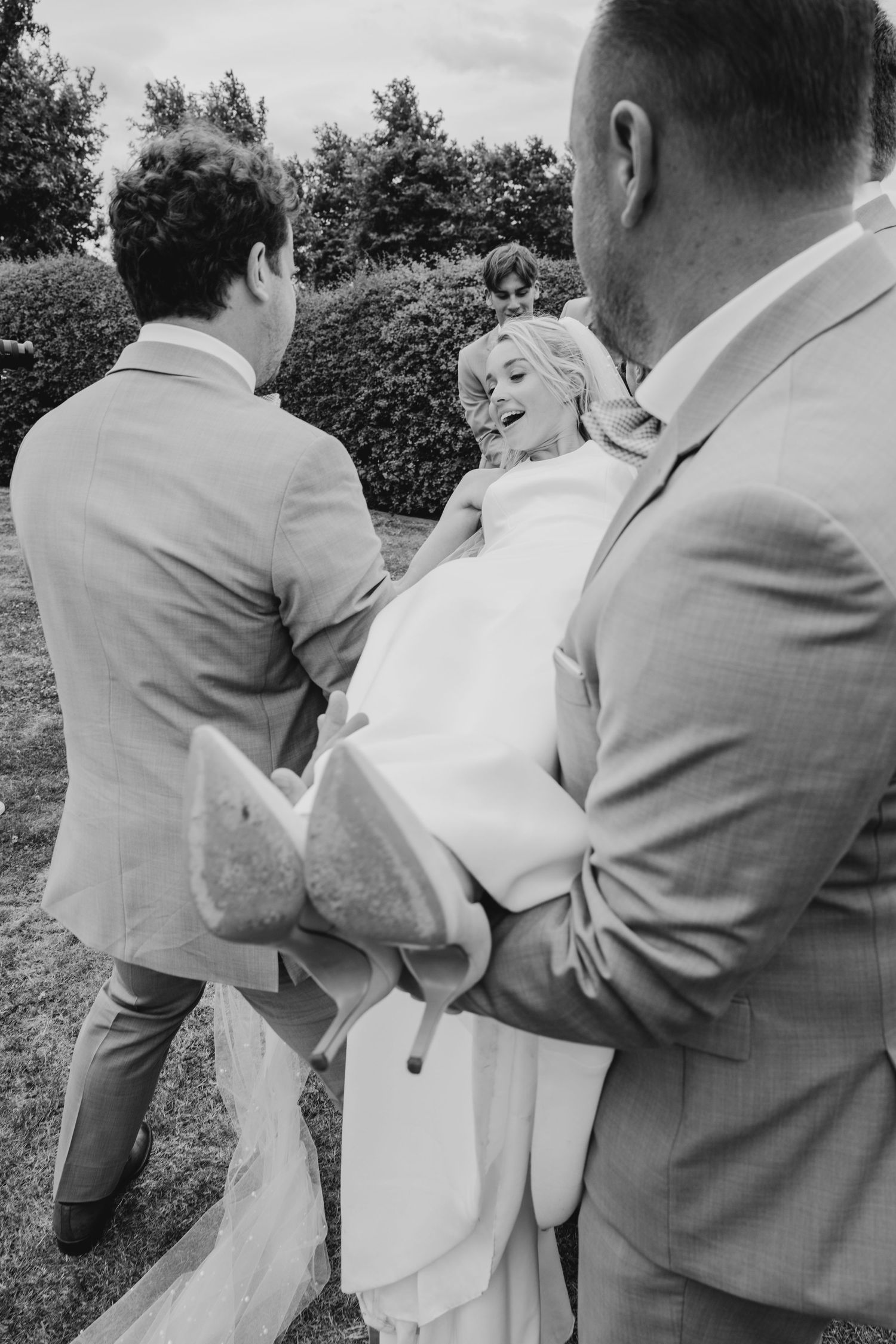 Black and white candid wedding party photo in a garden setting.
