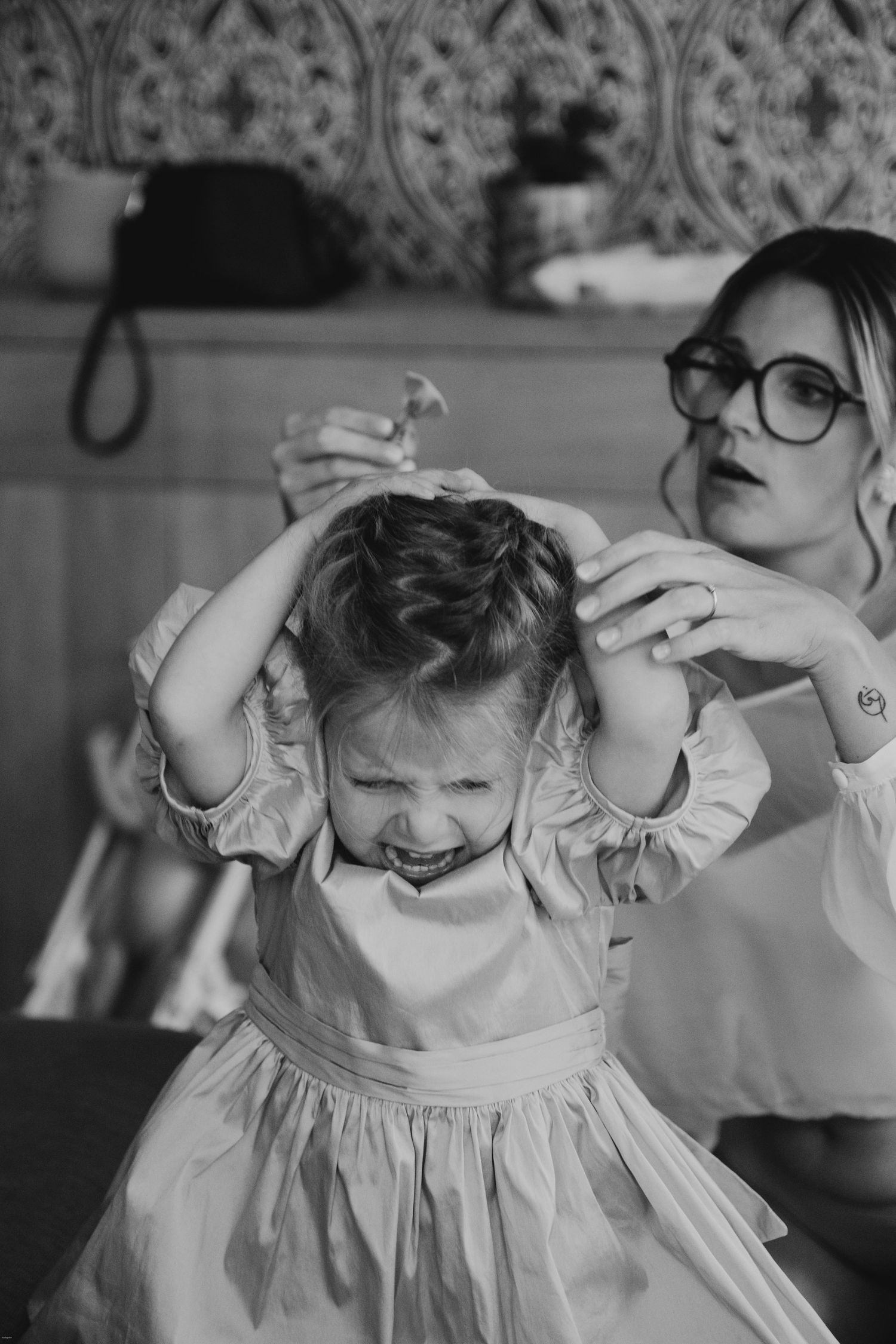 Black and white sequence showing a young child getting dressed in a frilly outfit.