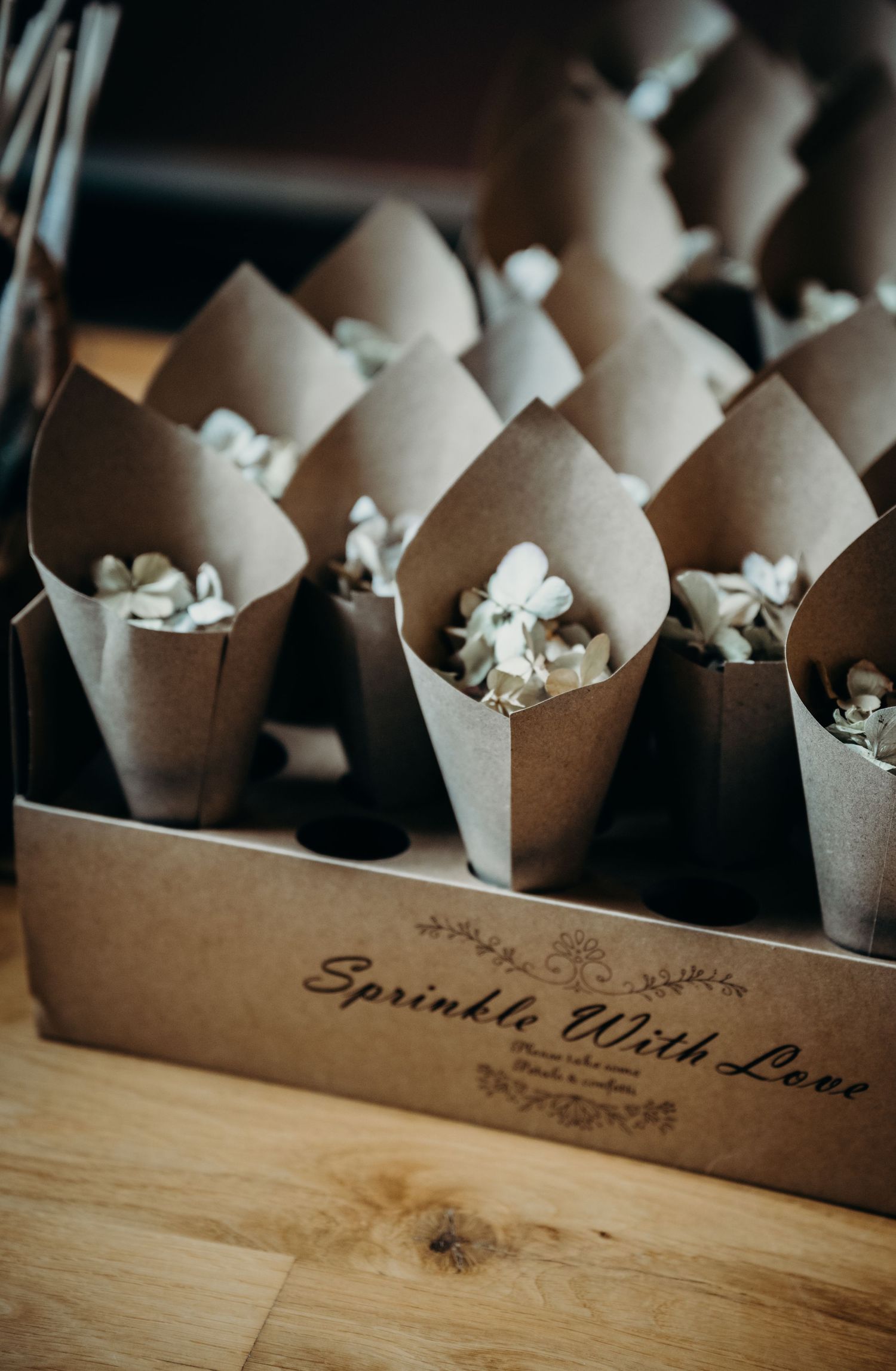 Brown paper confetti cones arranged neatly in a wooden box with decorative text.