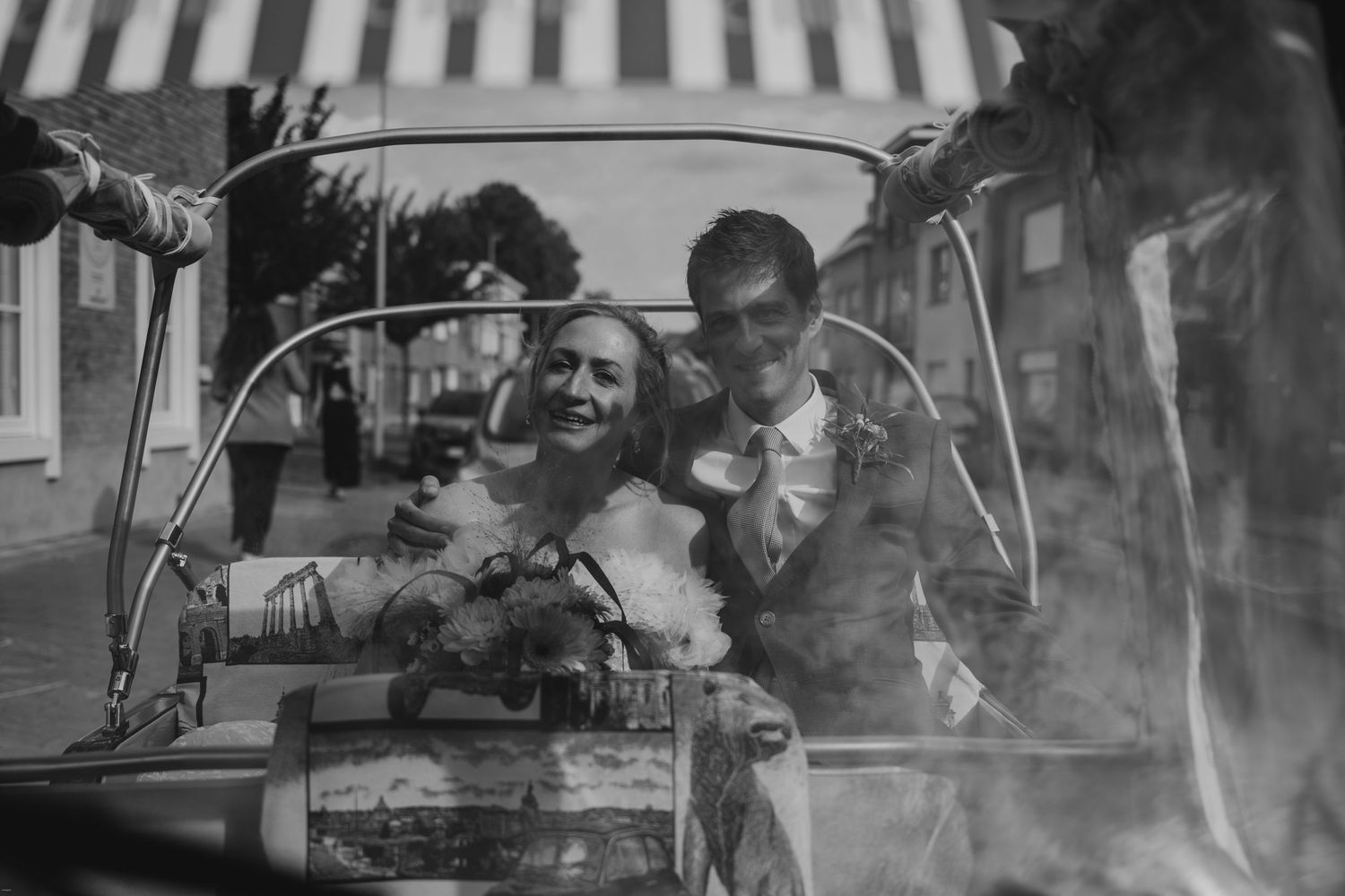 A vintage black and white photo of newlyweds in a classic car.