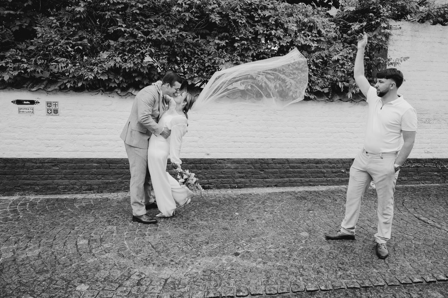 Wedding party walking casually across grass in black and white.
