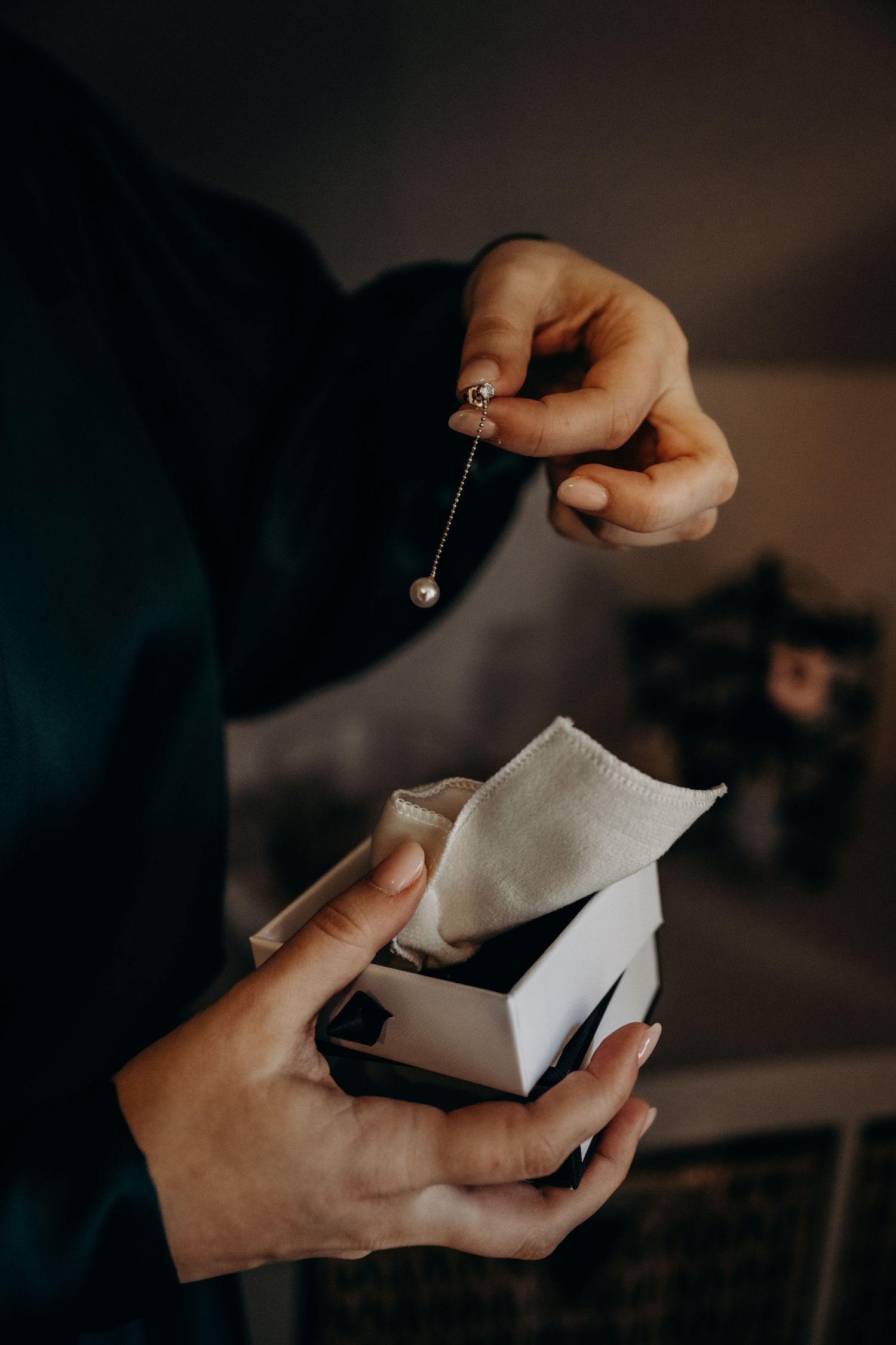 Hands carefully opening a delicate white package in dim lighting.
