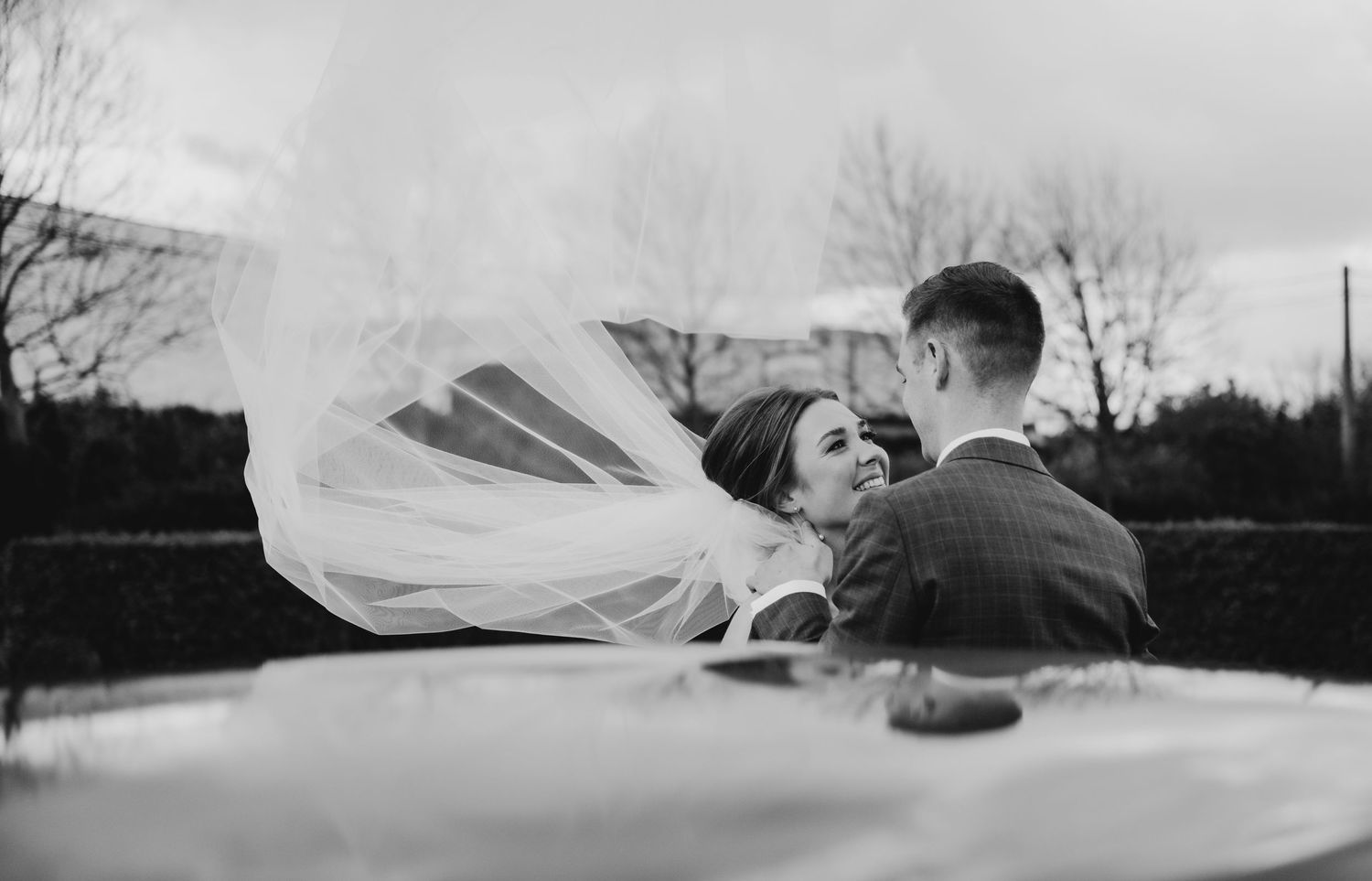 Flowing white wedding veil caught in the wind against a dramatic sky.