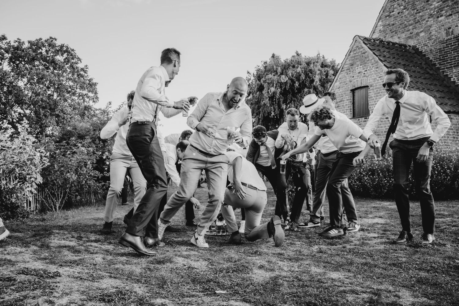 Black and white photo of guests dancing and jumping at an outdoor party.