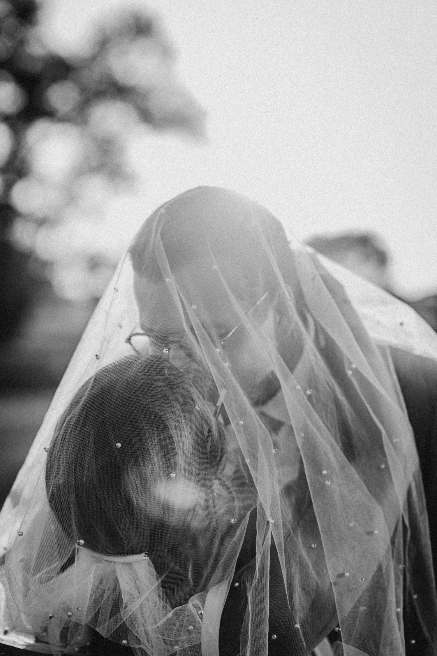 Artistic black and white close-up of a delicate bridal veil flowing in the breeze.