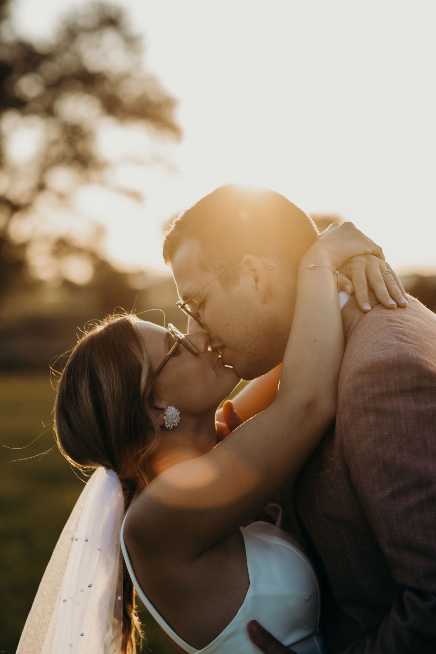 Sunset silhouette of a romantic wedding couple sharing an intimate moment.