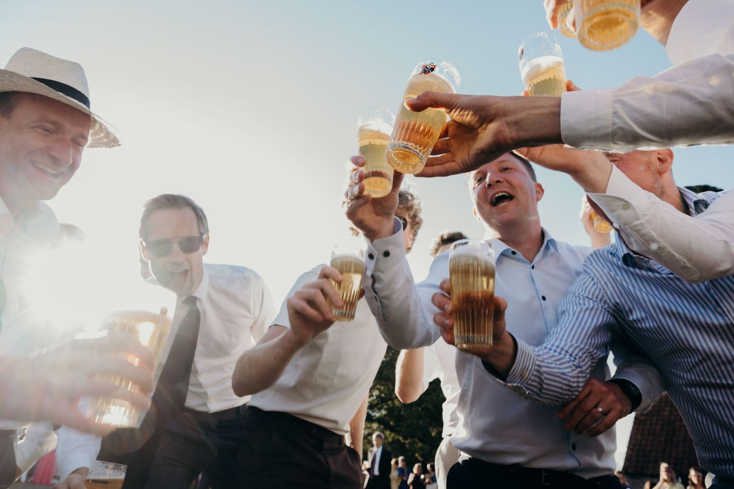 Group of friends toasting with beer glasses at an outdoor celebration.