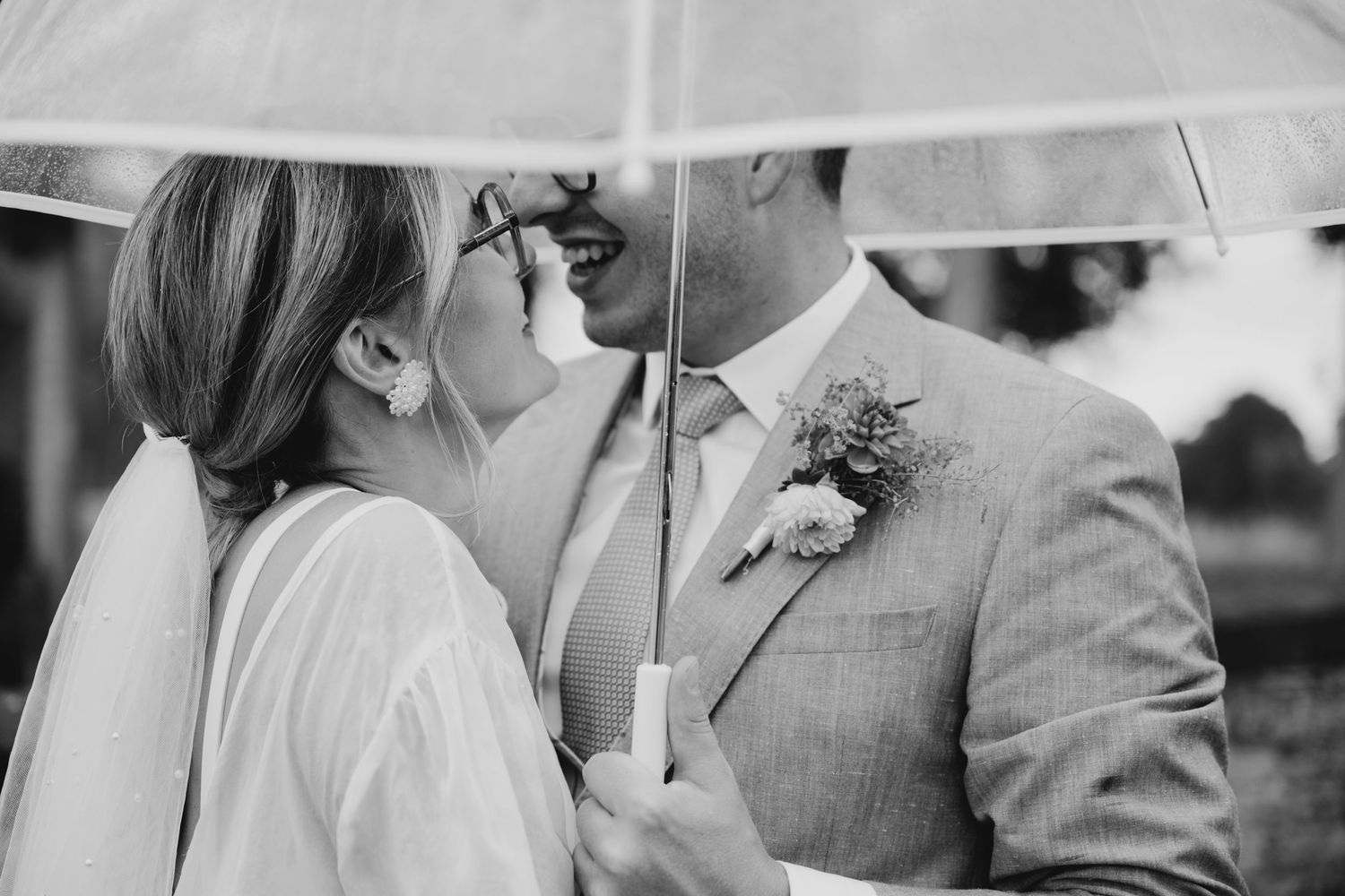Romantic moment shared under a white umbrella during an outdoor wedding.