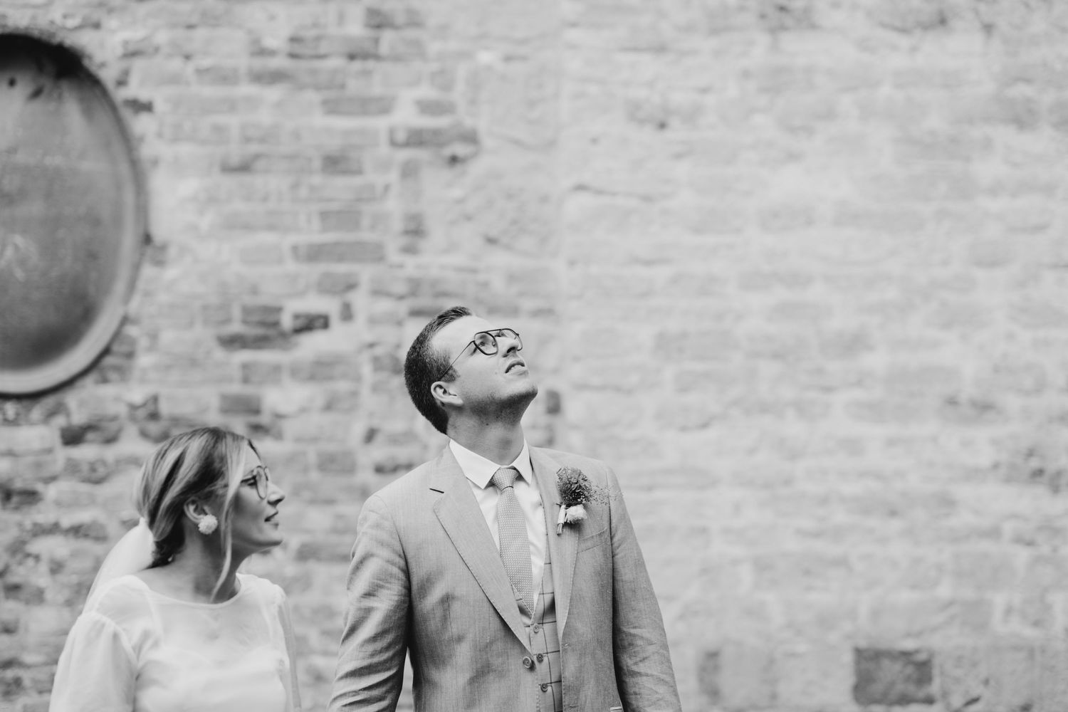 Black and white wedding portrait against rustic brick wall.