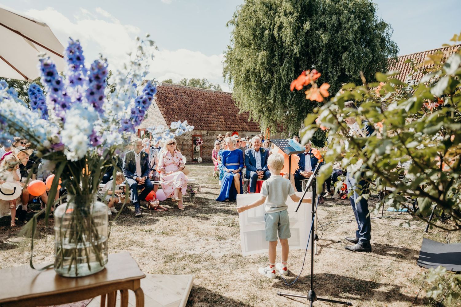 Outdoor wedding reception with colorful floral arrangements and guests enjoying the sunny atmosphere.