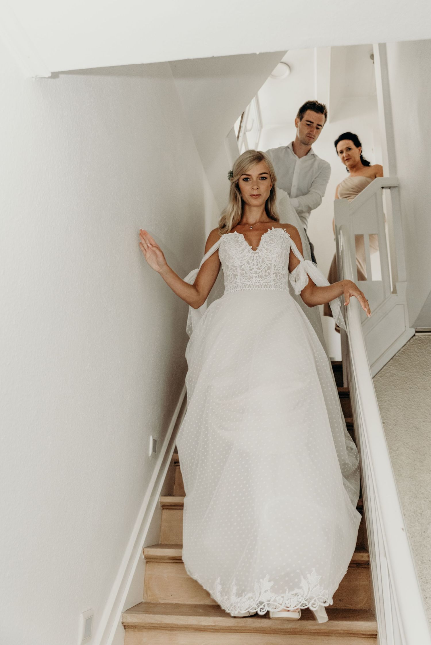 Bride descending elegant white staircase in full wedding gown.