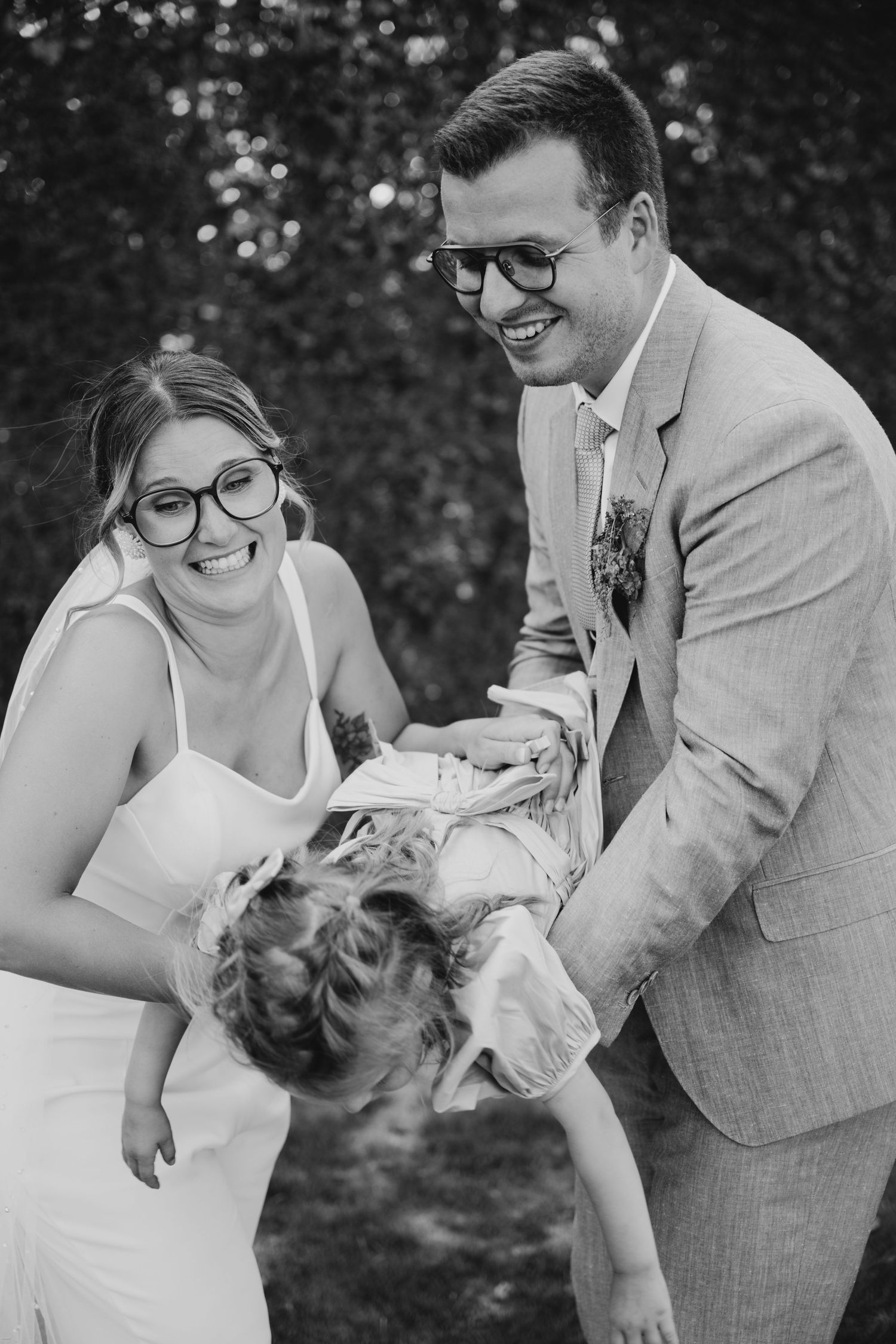 A couple shares a playful dip dance pose outdoors in formal attire.