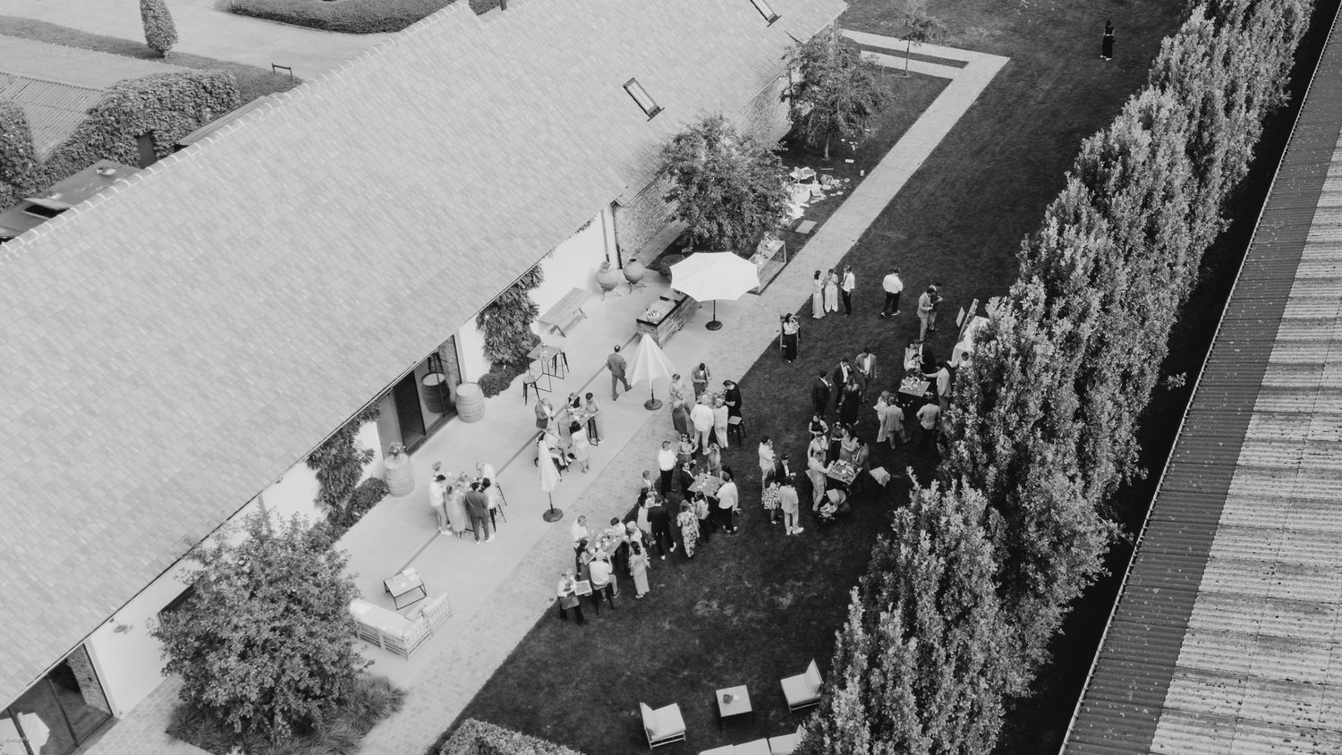 Aerial view of an elegant outdoor wedding ceremony setup with rows of white chairs.
