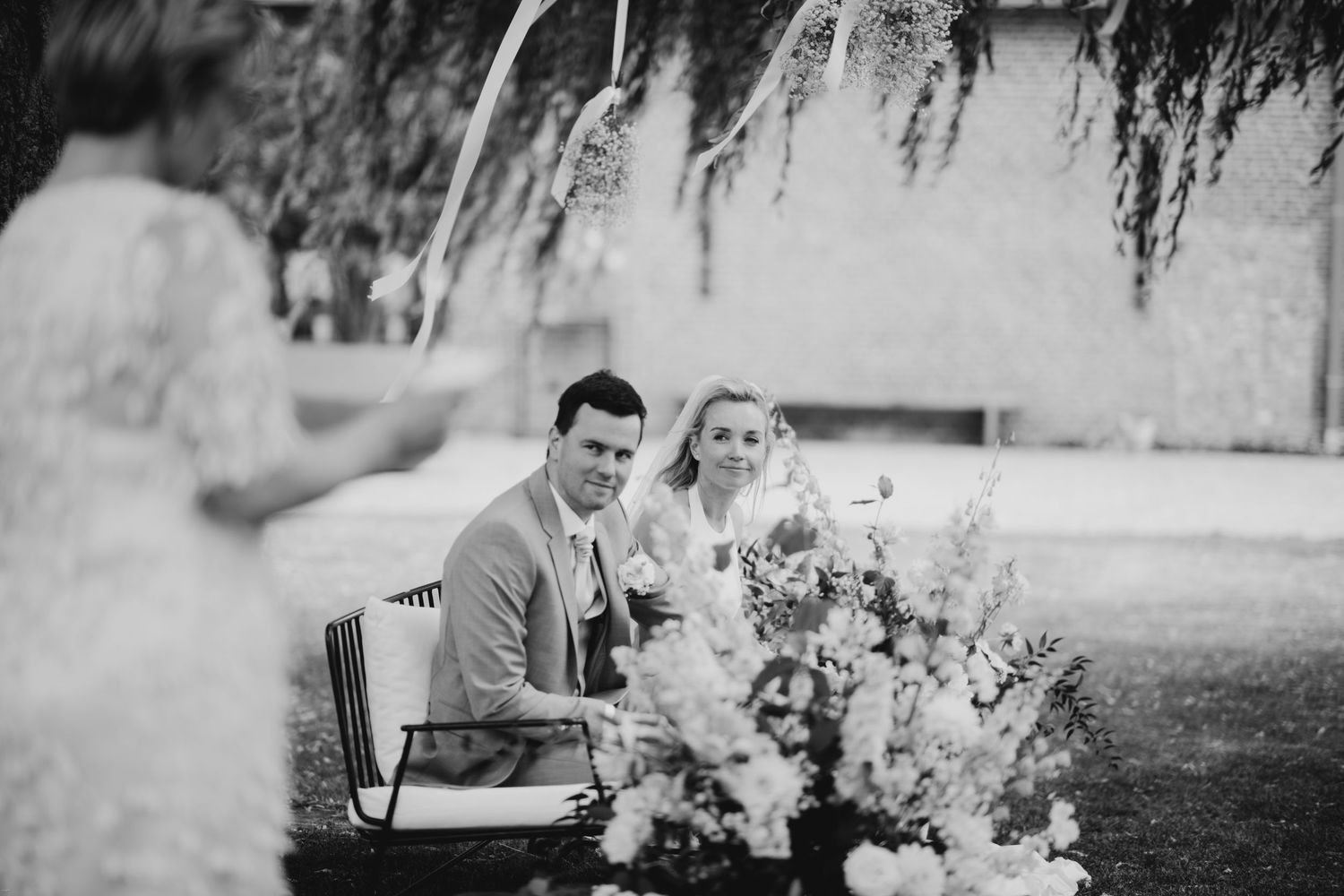 Romantic outdoor wedding scene with hanging floral decorations and garden setting.