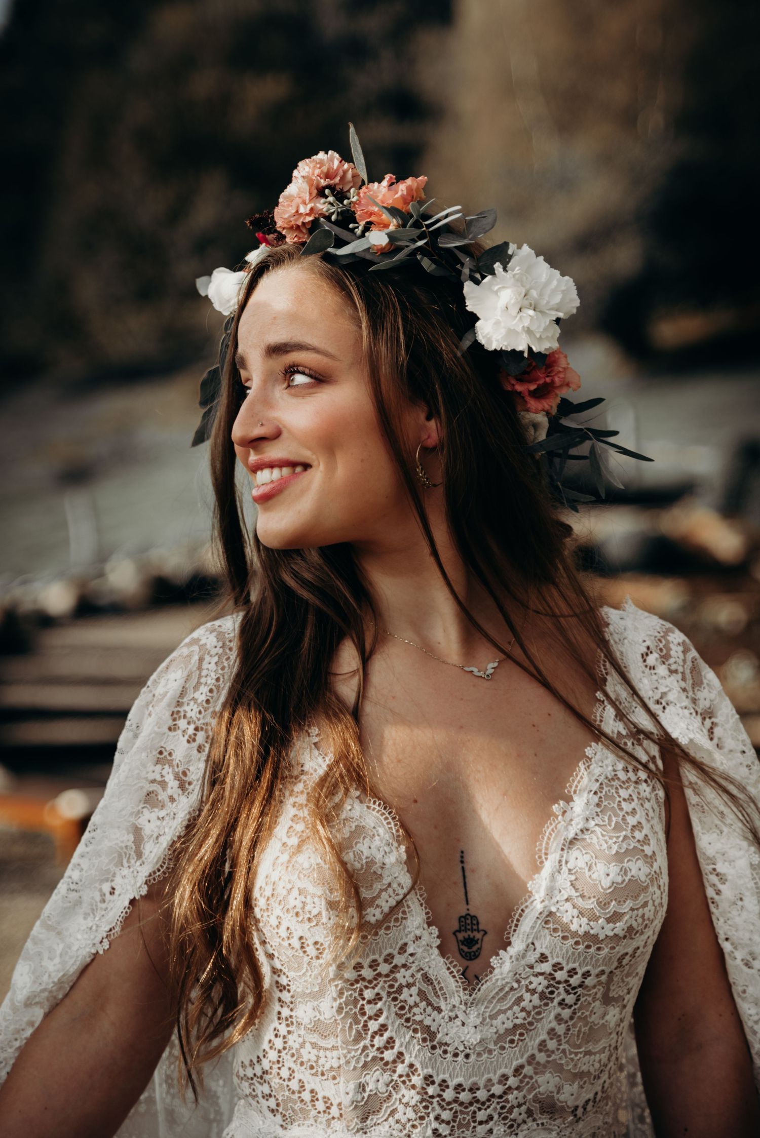 A bride wearing a delicate lace dress and floral crown smiles in a series of romantic outdoor portraits.