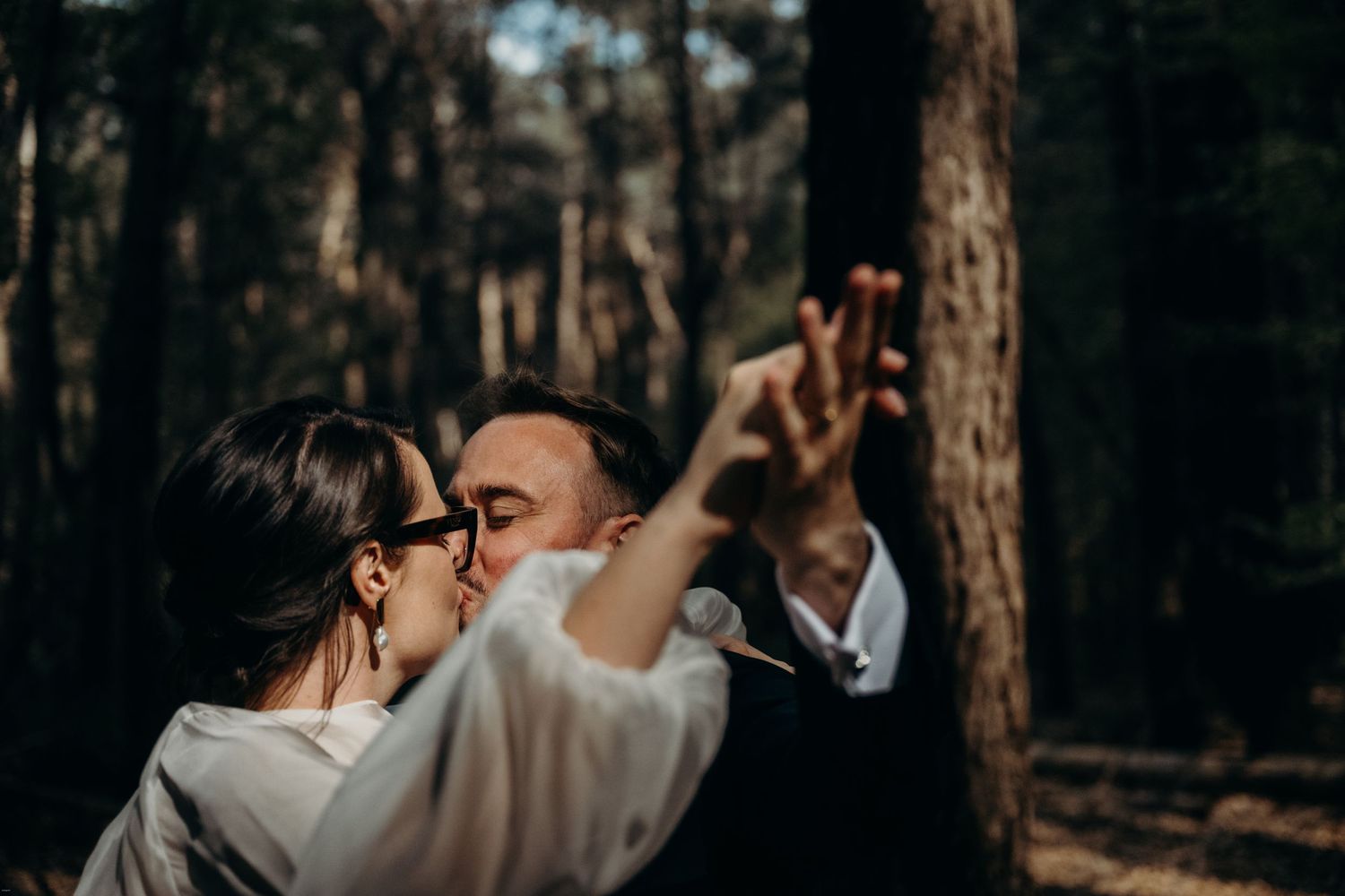 Romantic forest photoshoot among tall pine trees in moody lighting.