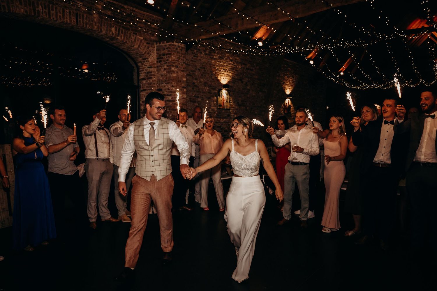 Wedding reception dance party with string lights and exposed brick walls.