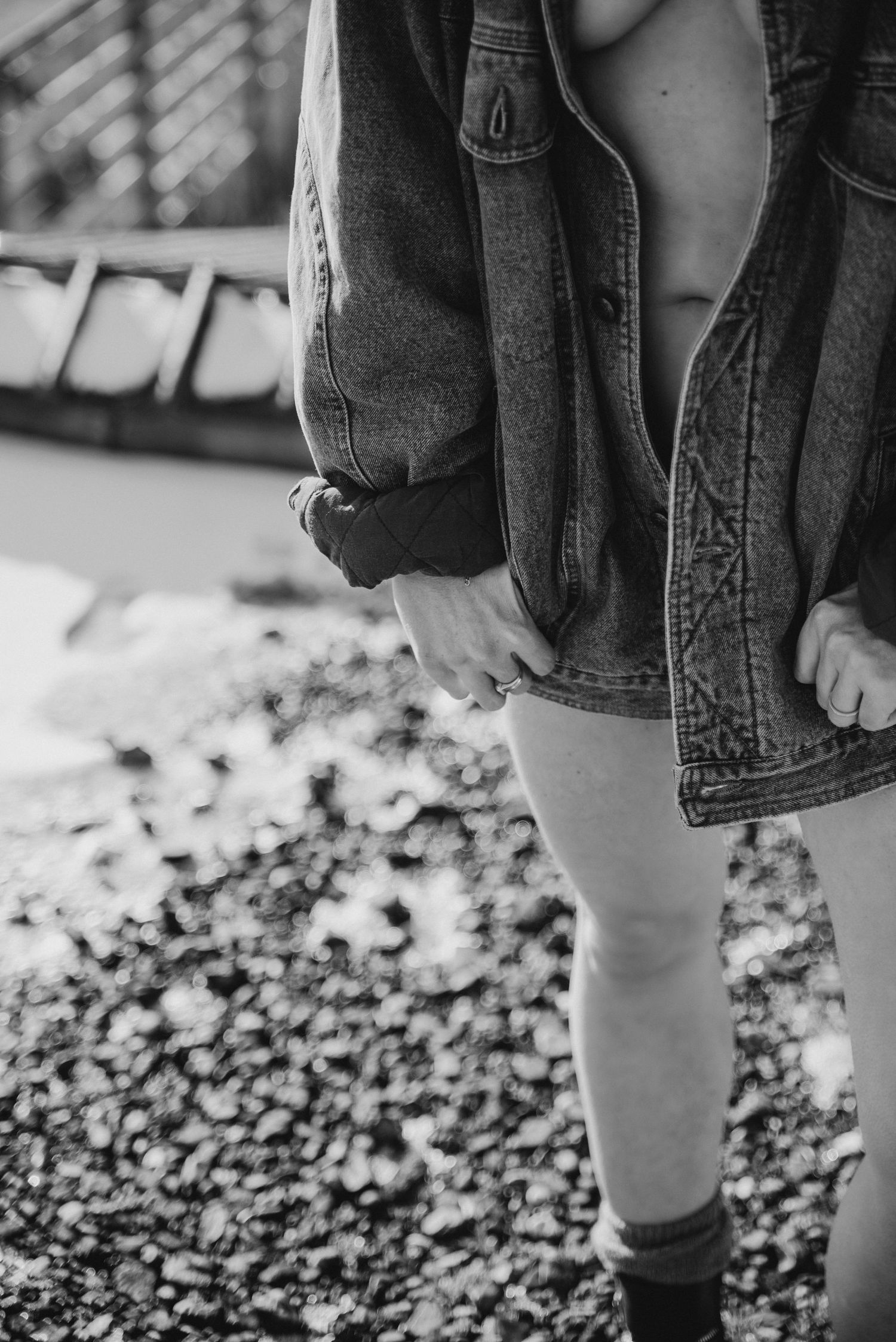 Black and white photo of legs in denim shorts walking on a bed of fallen autumn leaves.