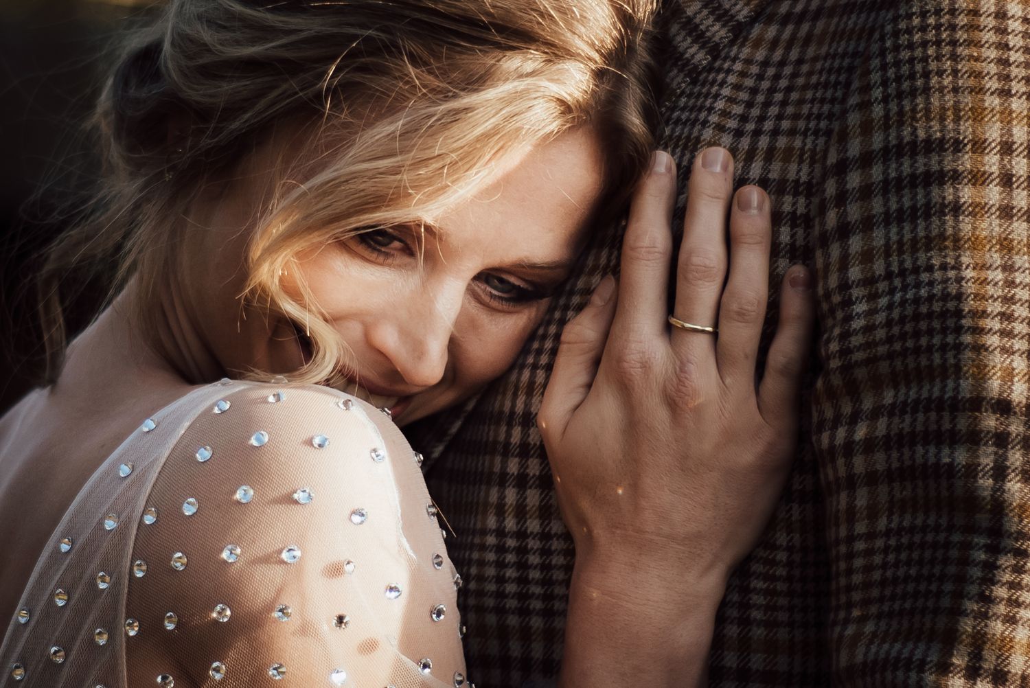 Close-up shot of couple in romantic embrace wearing polka dot dress and plaid jacket.