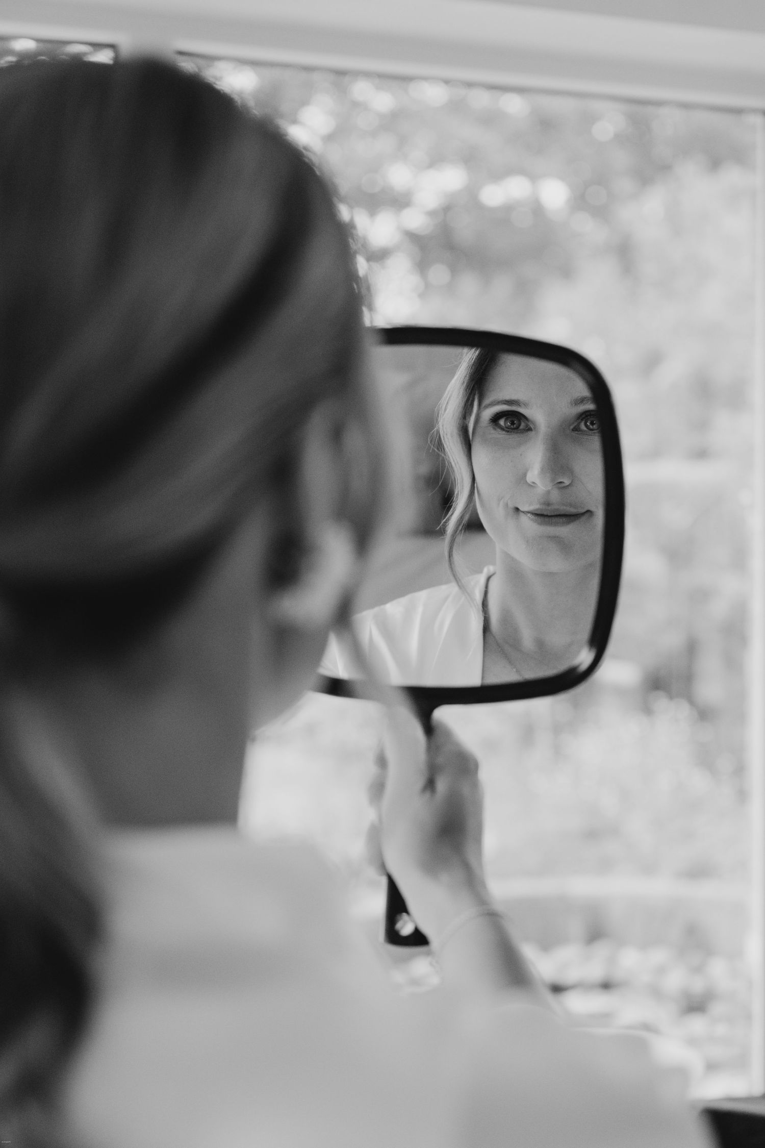 Artistic black and white shot reflected in car side mirror during wedding preparations.