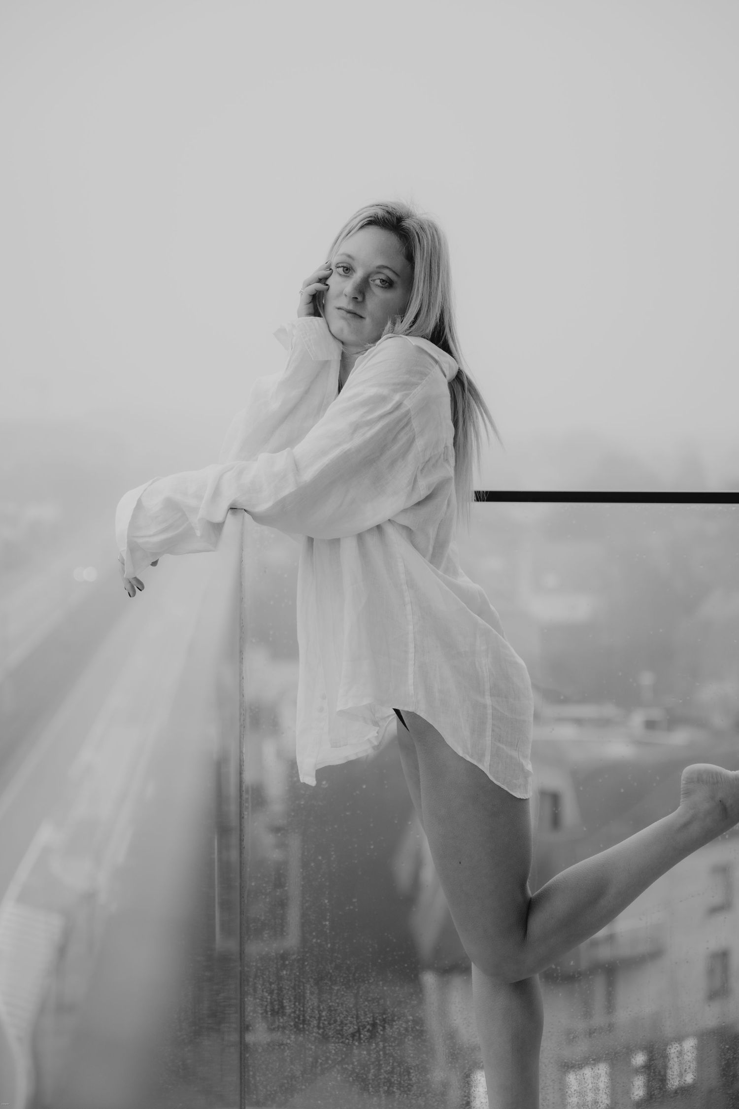 A series of ethereal black and white photos showing a figure in a white shirt moving against a misty urban backdrop.