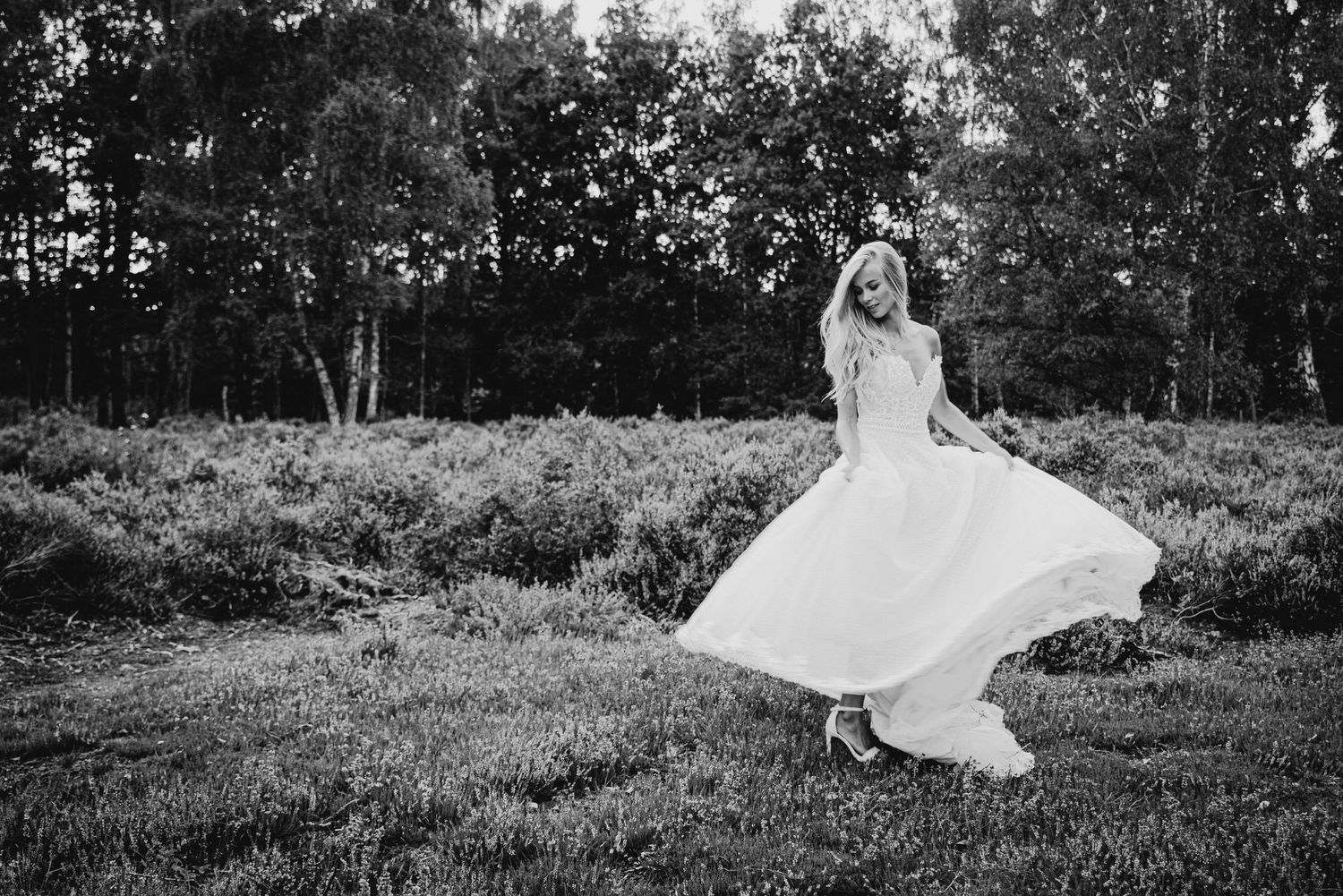 Black and white photo of a wedding dress flowing in the breeze on a hillside.