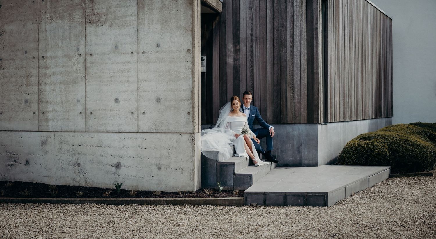 Modern concrete building exterior with minimalist architecture and gravel landscaping.