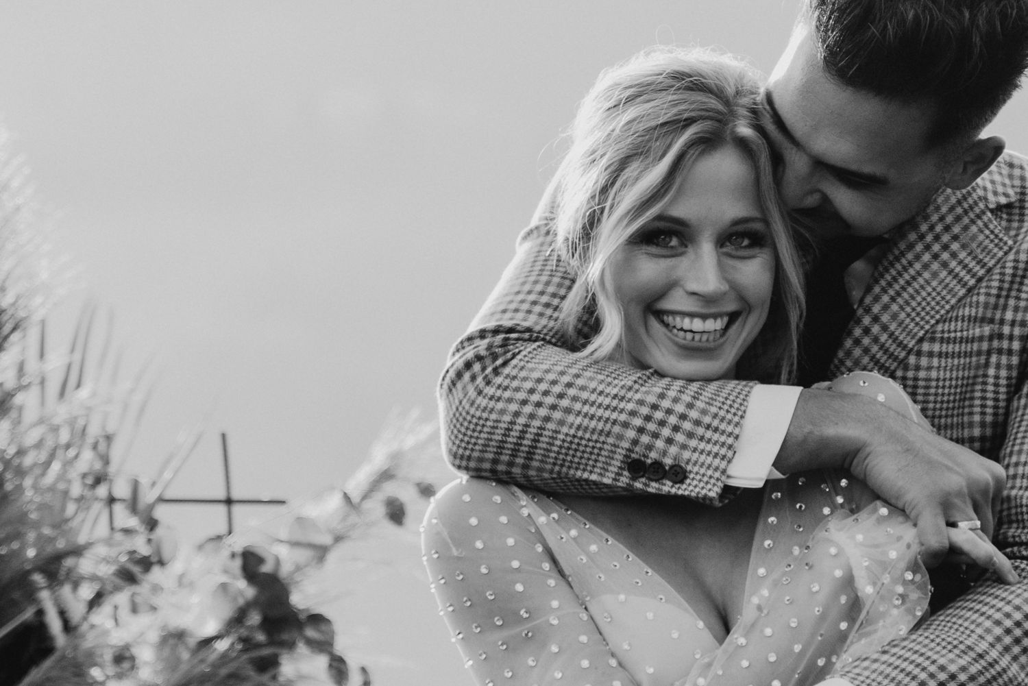Intimate wedding portrait showing a couple in formal attire sharing a tender moment outdoors.