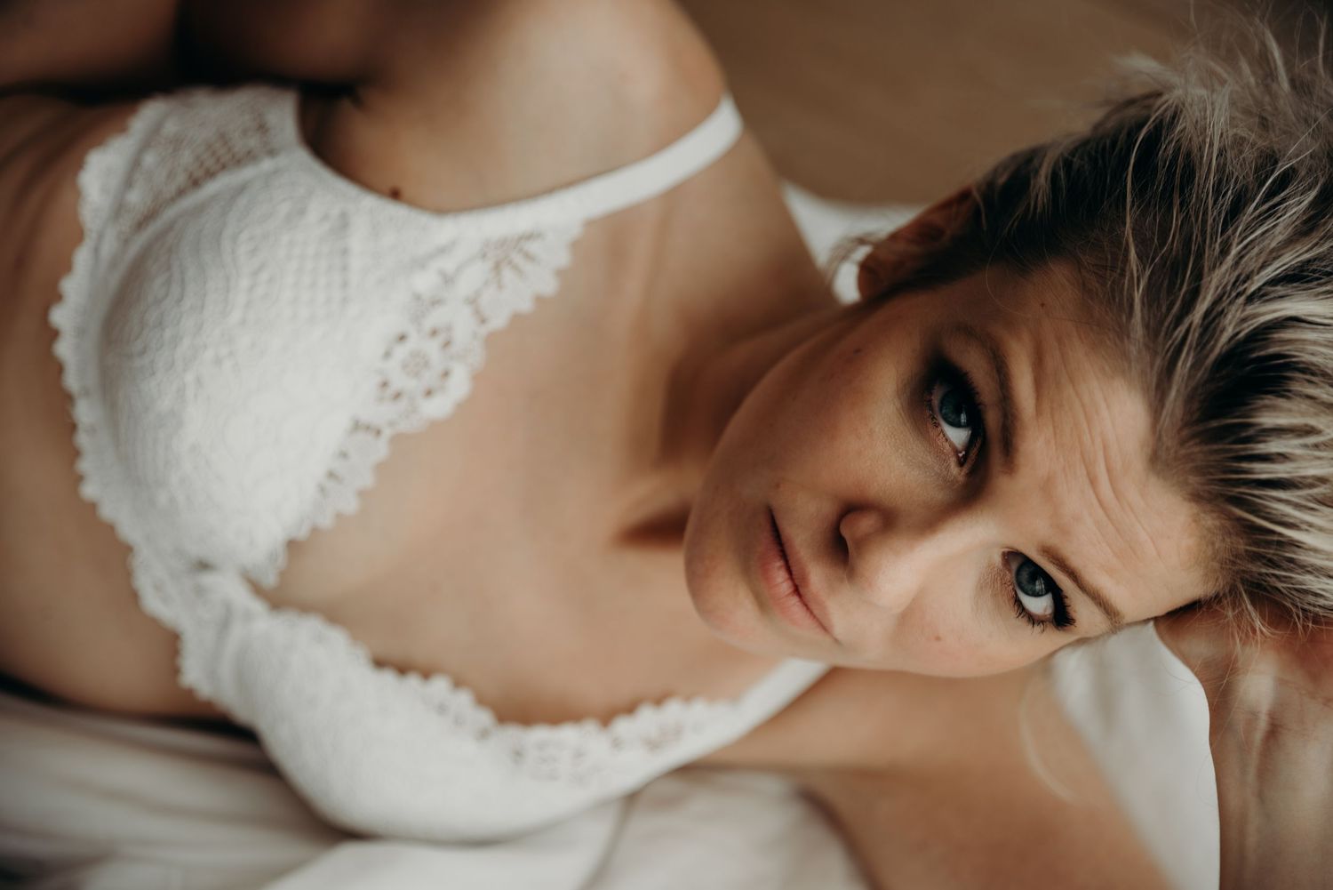 Close-up details of a white lace wedding dress with delicate embroidery and soft lighting.
