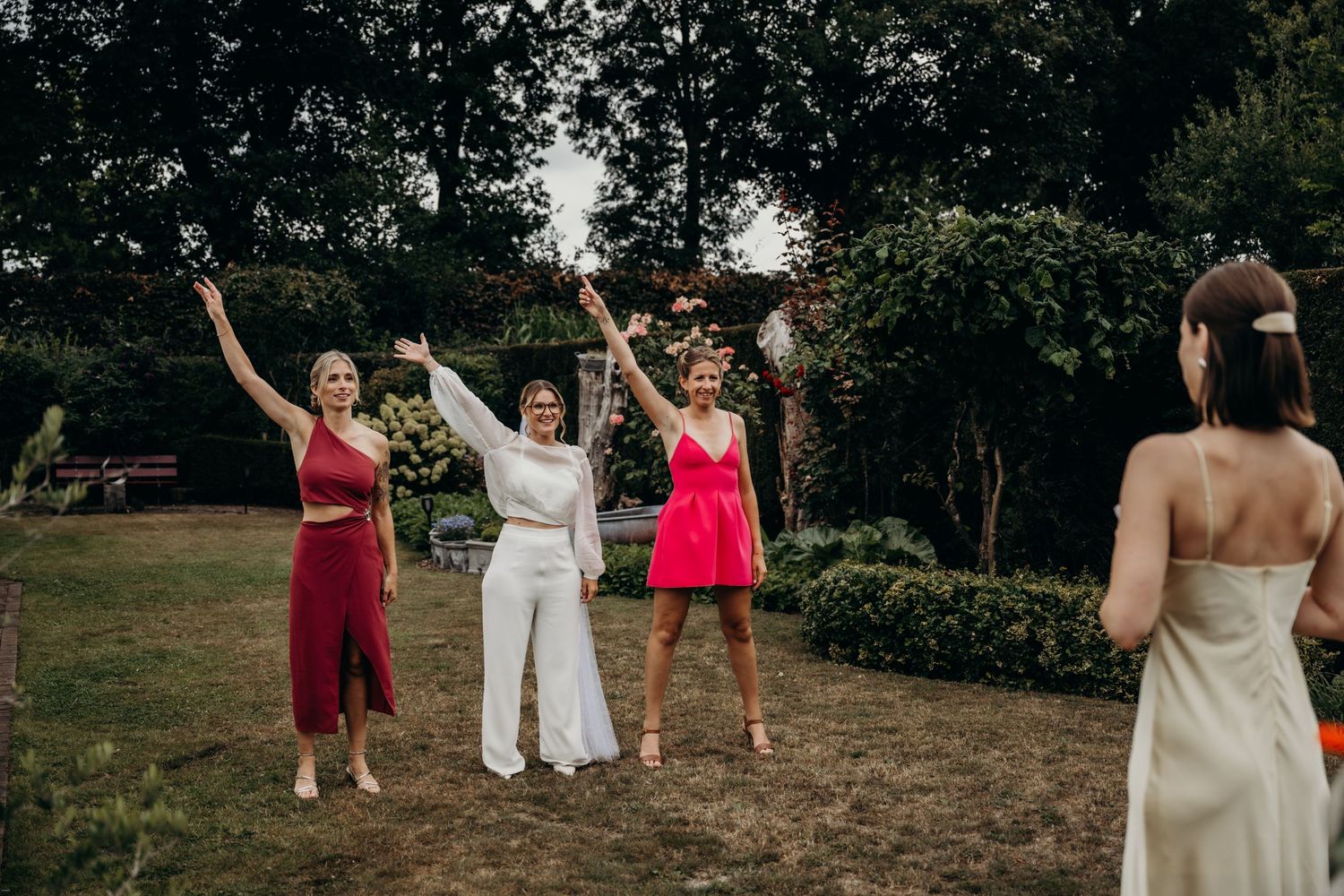 Wedding party celebrating outdoors with joyful poses and raised arms.