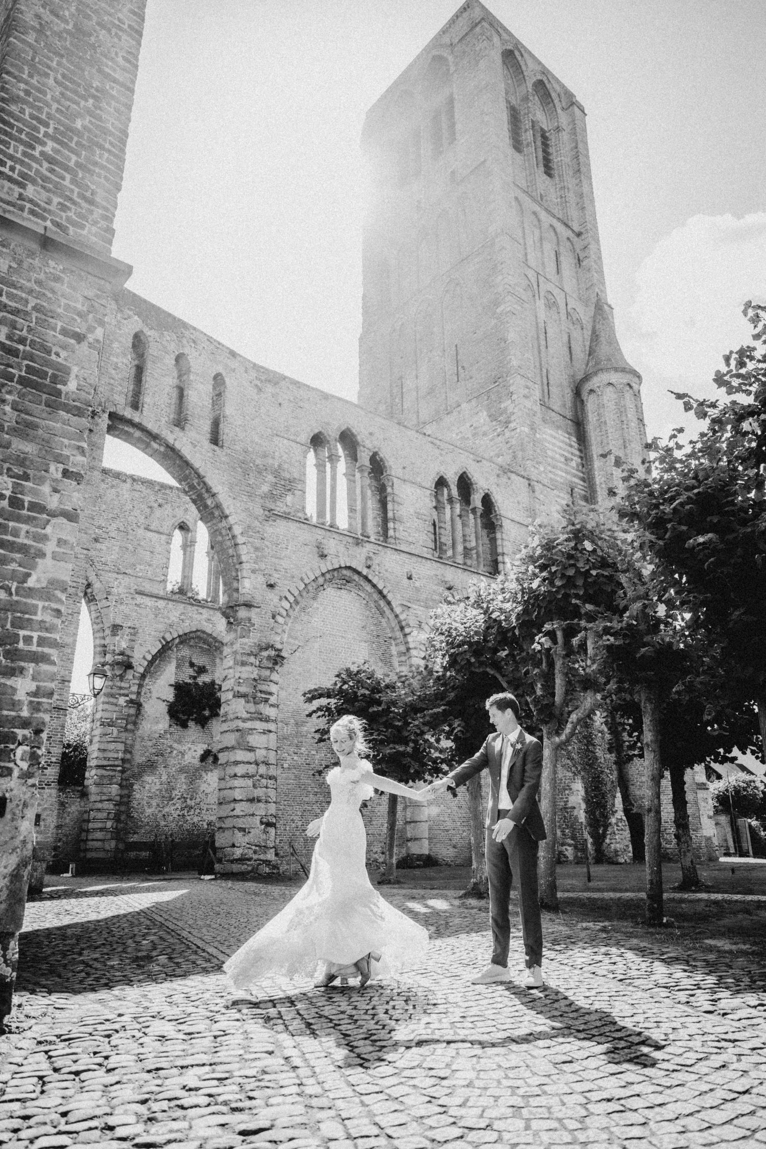 A romantic wedding photoshoot sequence against historic stone church ruins with dramatic arches and cobblestone ground.